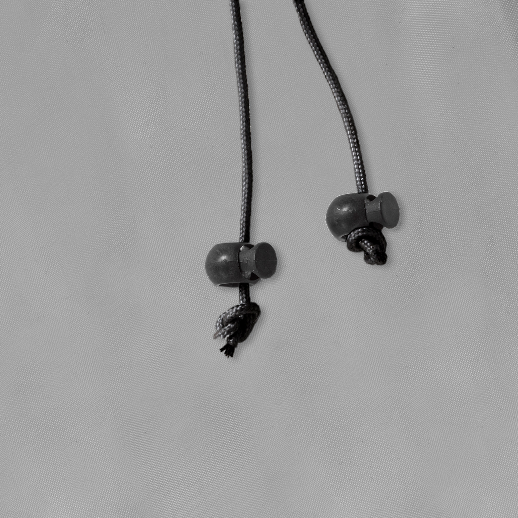 Zwei Kordeln mit Stoppern auf einer textilen Oberfläche