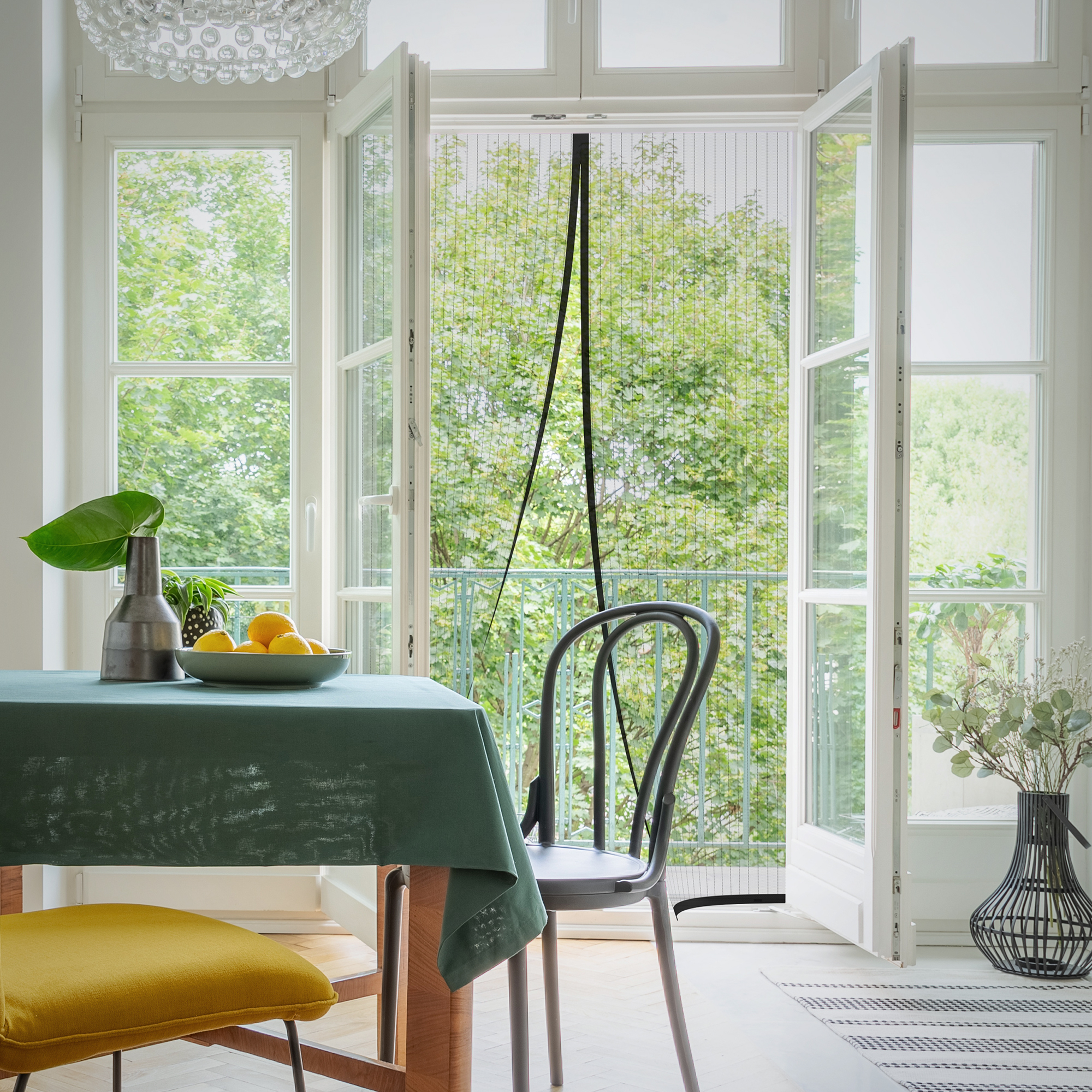 Fliegengitter-Magnetvorhang an geöffneter Tür im Wohnraum mit Tisch und Stuhl