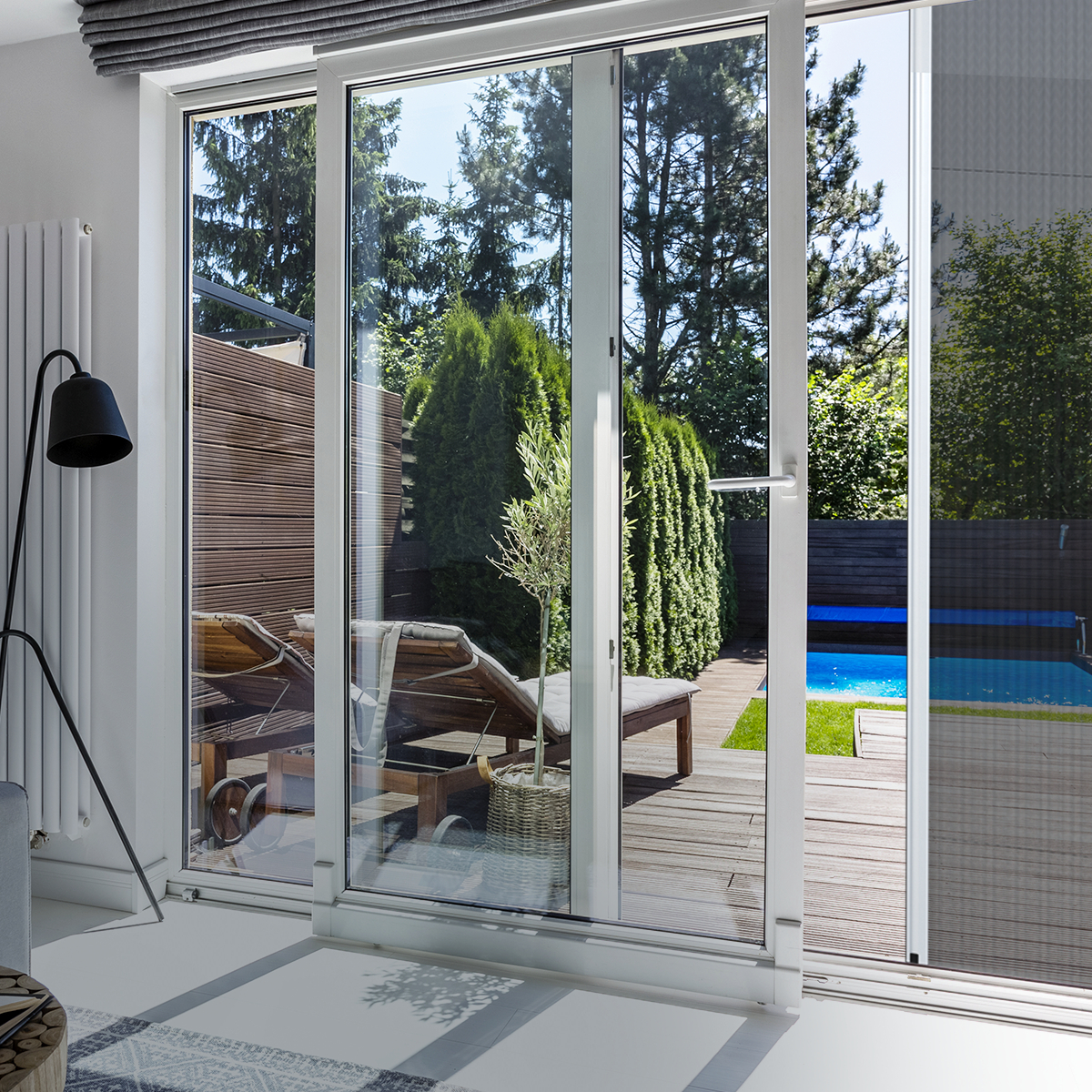 Schiebetür mit Blick auf Terrasse und Garten mit Pool und Liegestühlen