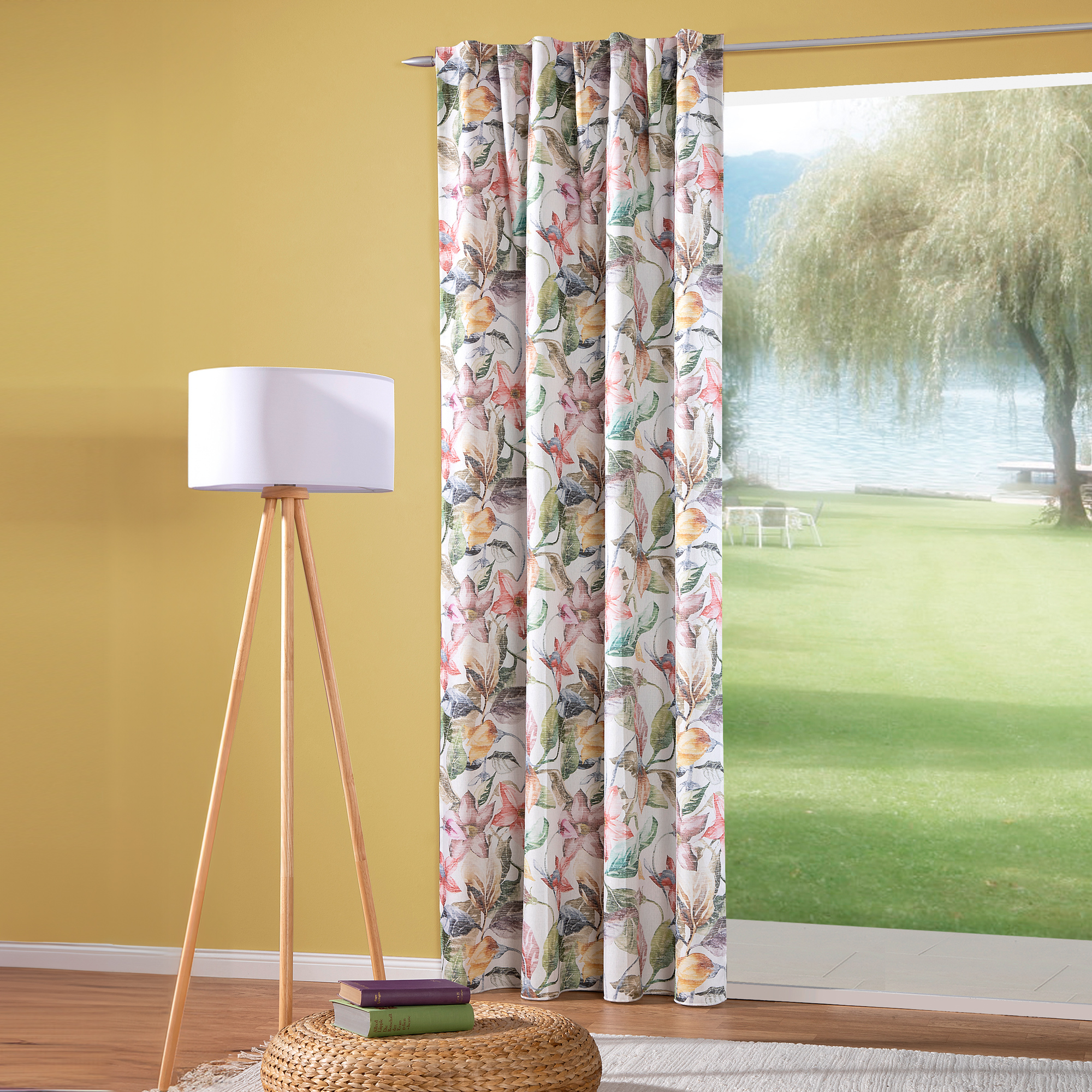 Vorhang mit Schlaufenband vor Fenster, daneben Stehlampe und Korbtisch mit Büchern