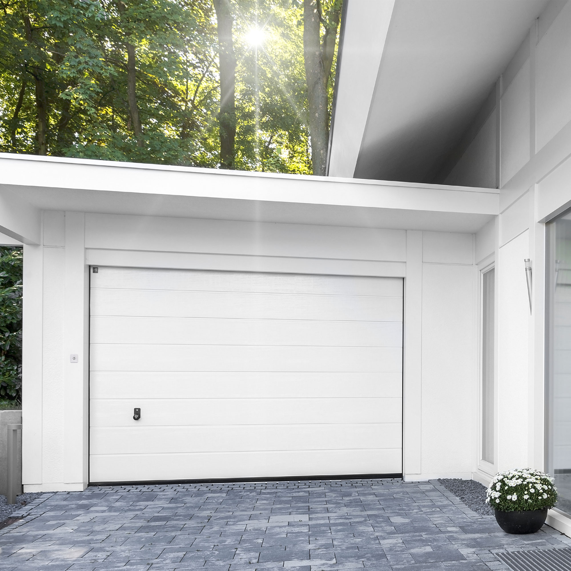 Garagentor mit Schlüsselschalter für Antriebssystem ML/JL, umgeben von moderner Architektur