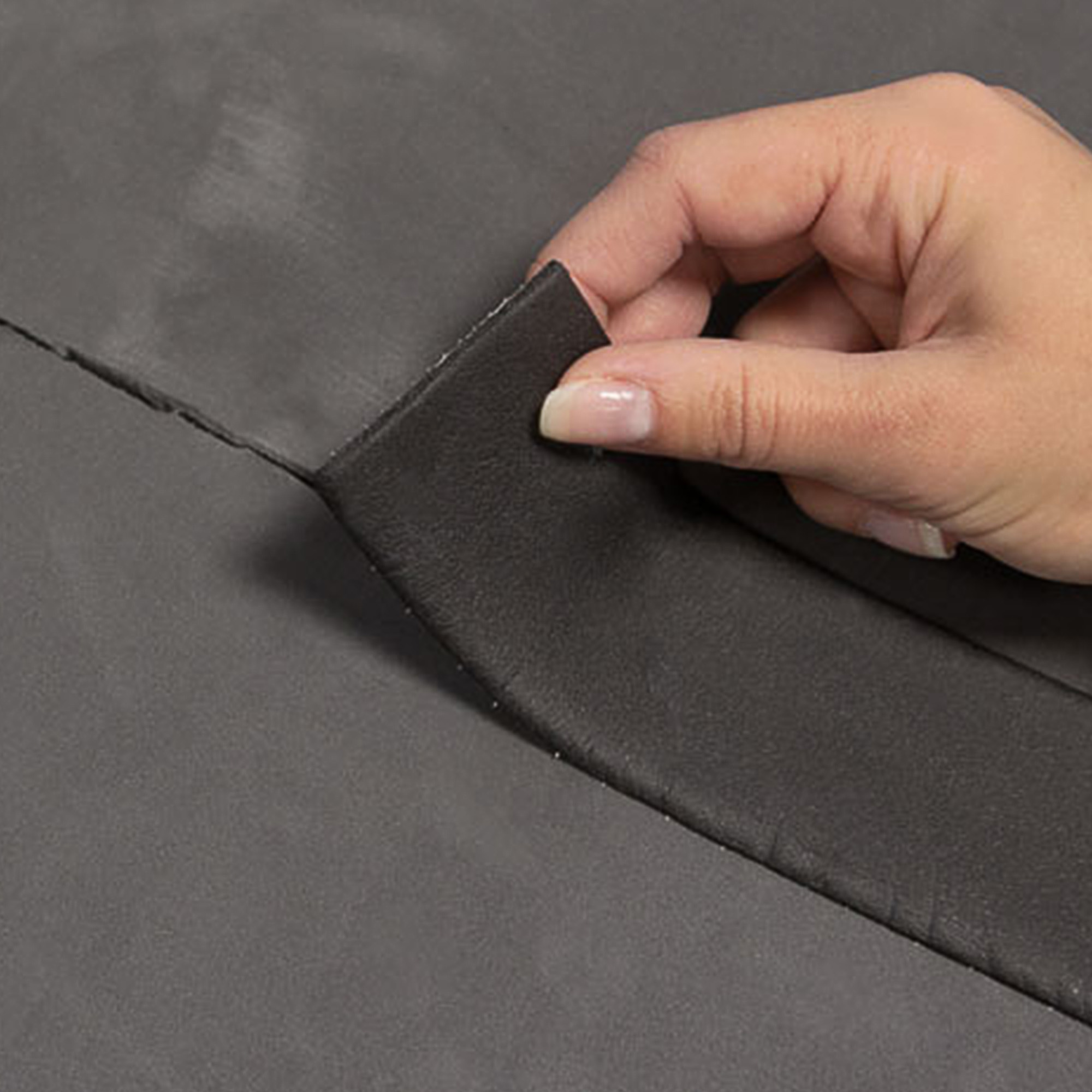 Hand zieht Kautschuk-Dichtband von Isoliermatte ab