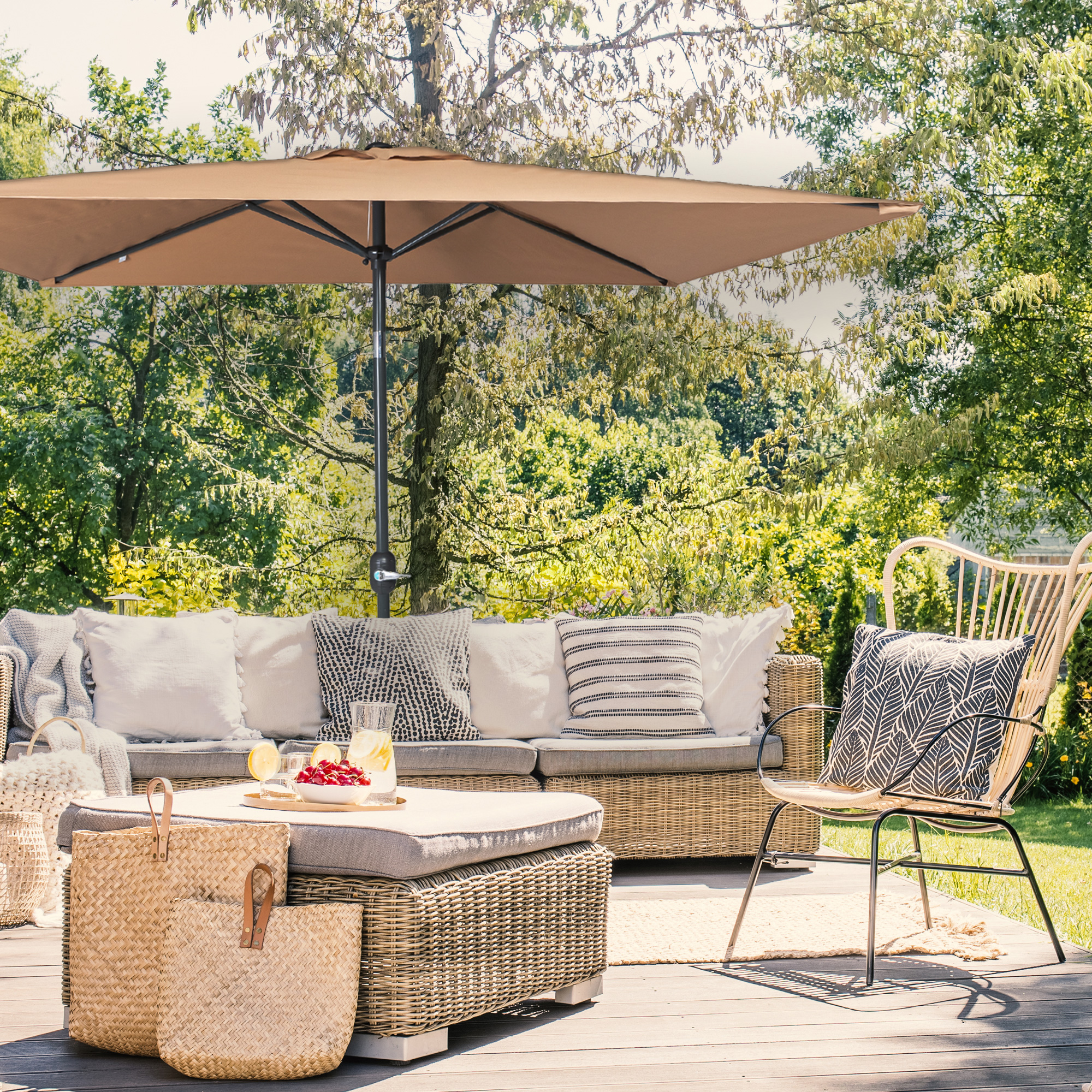 Kleiner, knickbarer Sonnenschirm über einer Terrasse mit Sitzmöbeln und Pflanzen im Hintergrund