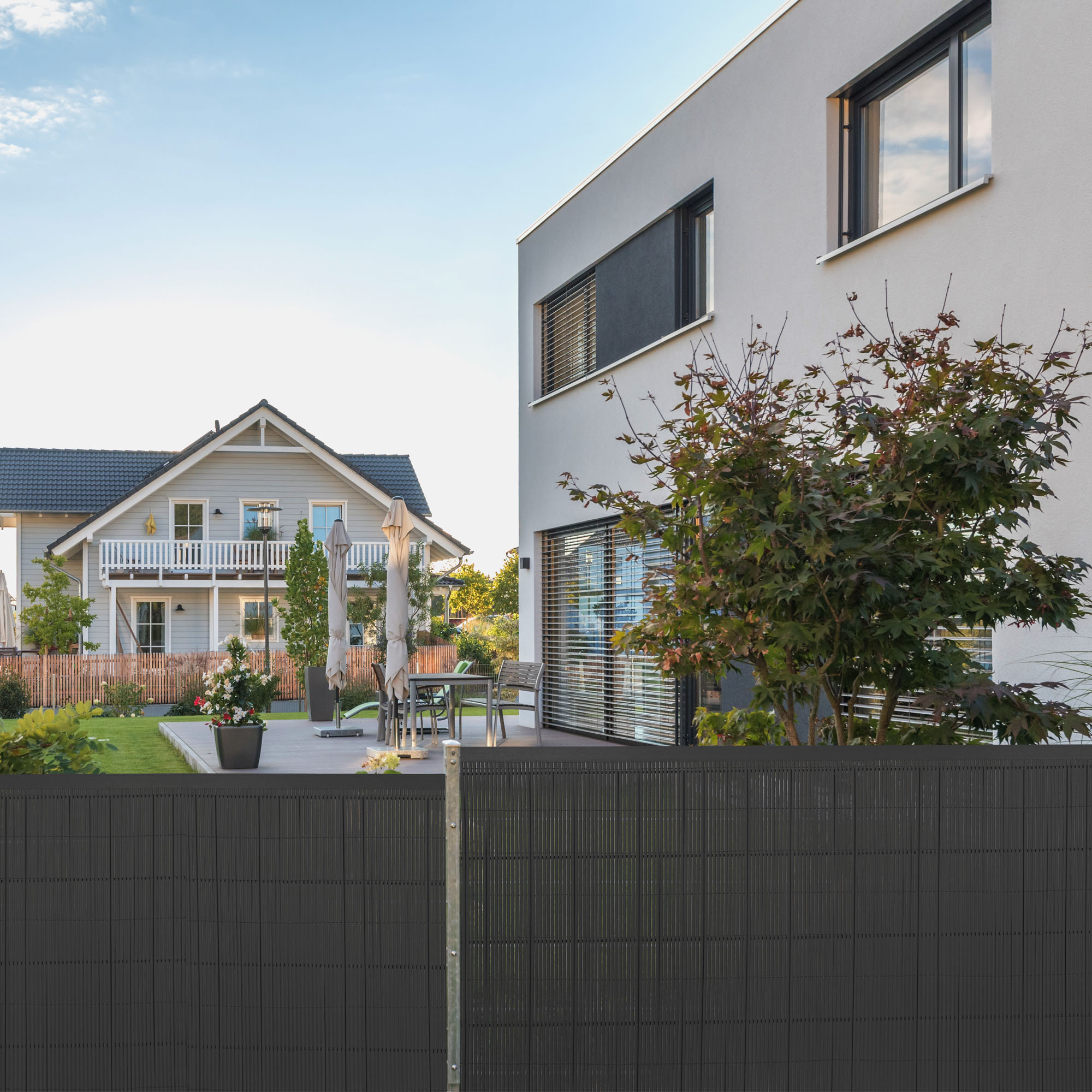 Bambuszaun vor einem Garten mit Haus im Hintergrund