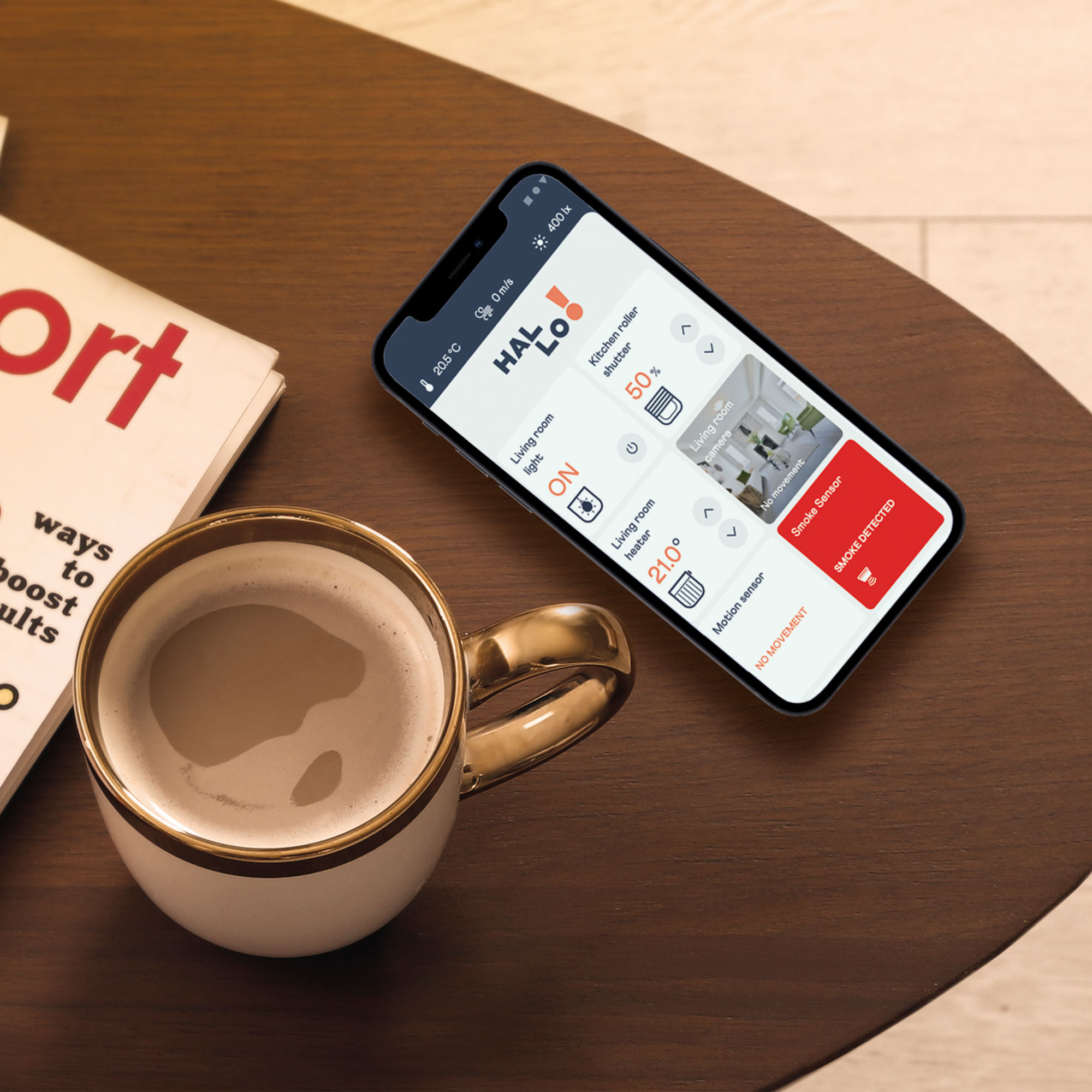 Smartphone mit geöffneter Smart-Home-App auf Tisch neben Tasse und Magazin