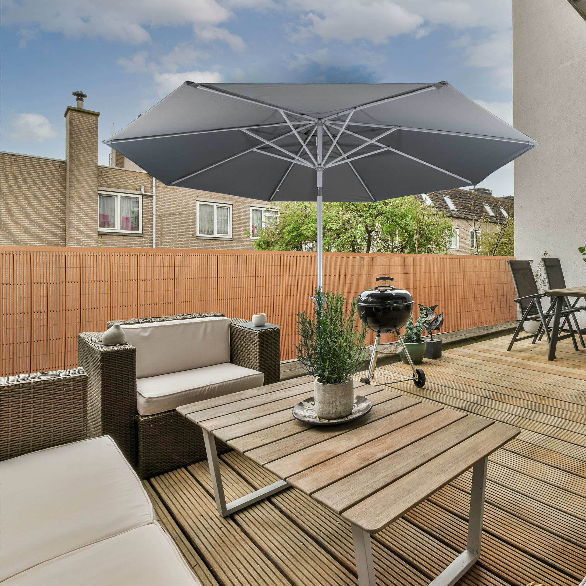 Terrasse mit Sichtschutzmatte aus Bambus, Gartenmöbeln und Sonnenschirm