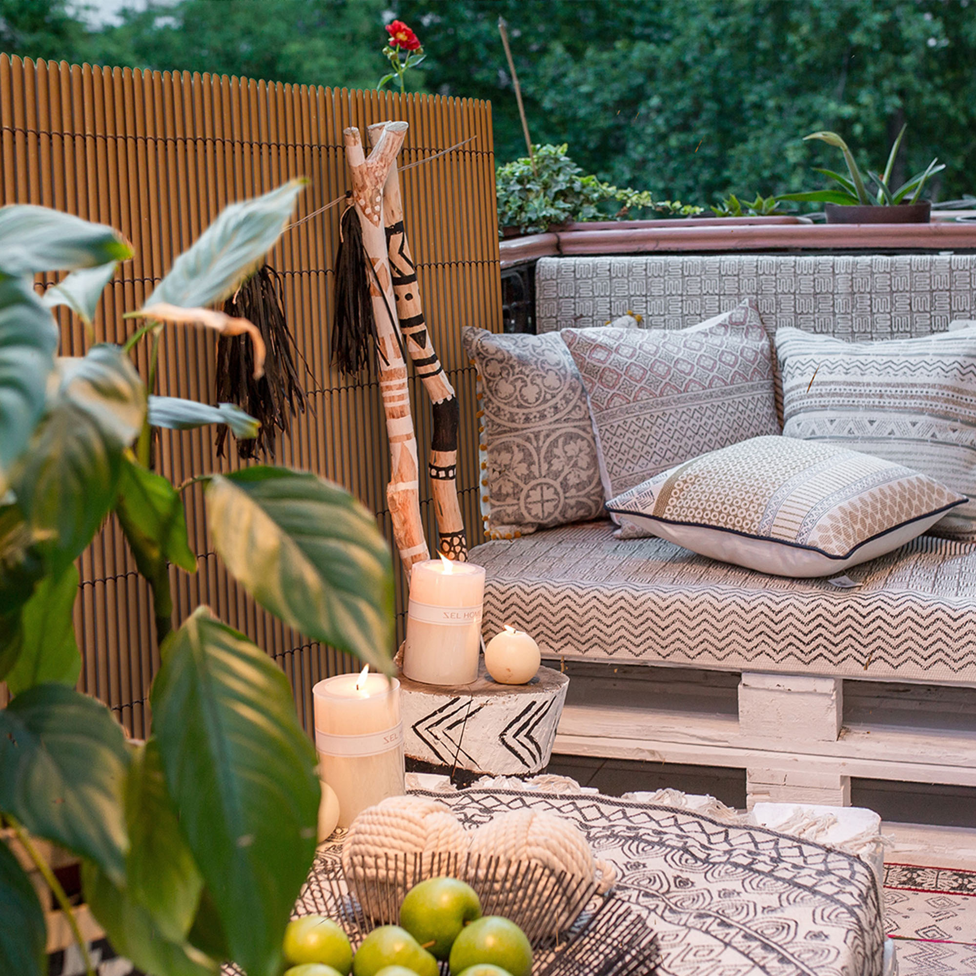 Terrasse mit Sichtschutzmatte, Sitzbereich, Kissen, Pflanzen und Dekorationselementen