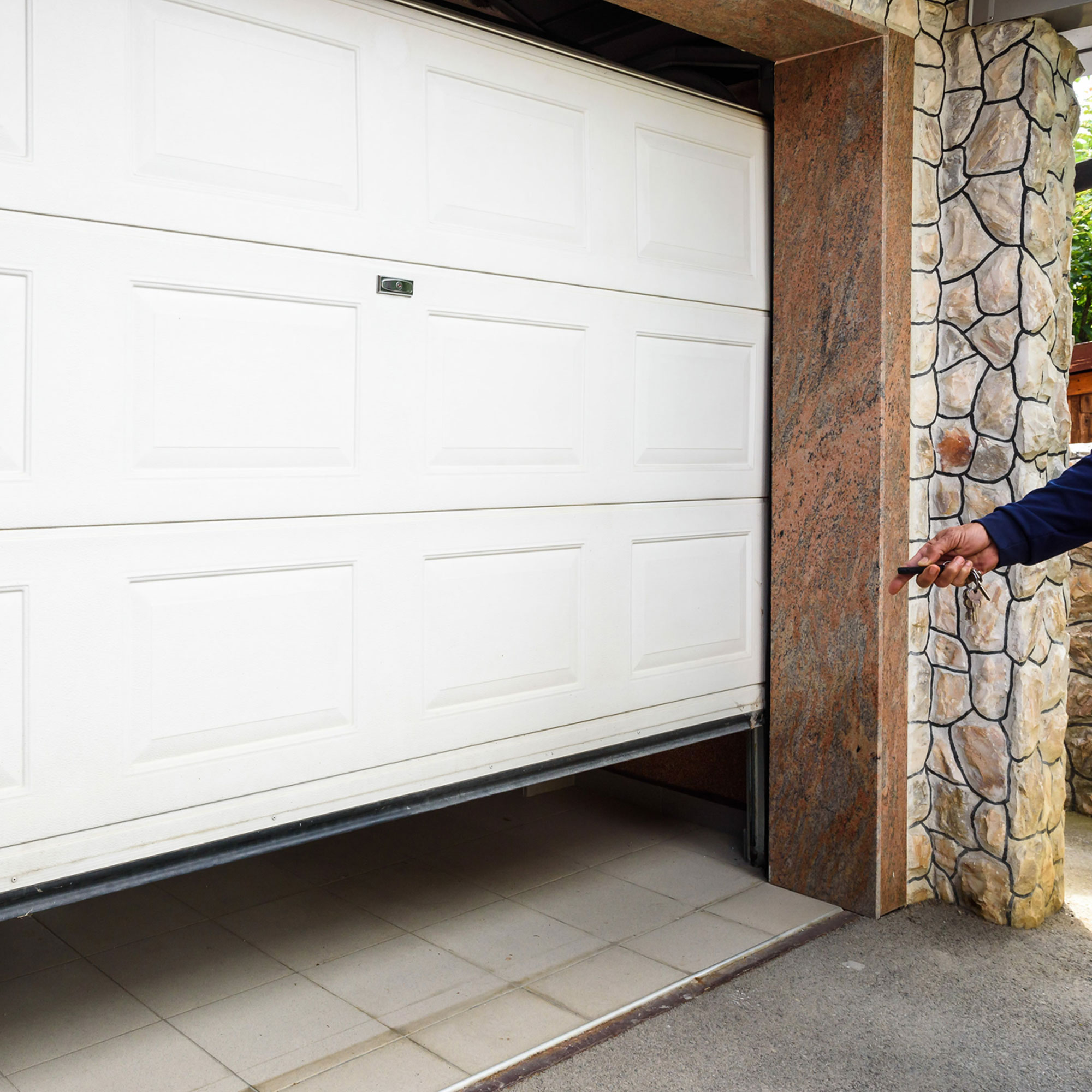 slider_image_0193074c22f67e94a0ec06180a298e97 Garagentor mit Antriebssystem, teilweise geöffnet, Person hält Fernbedienung in der Hand