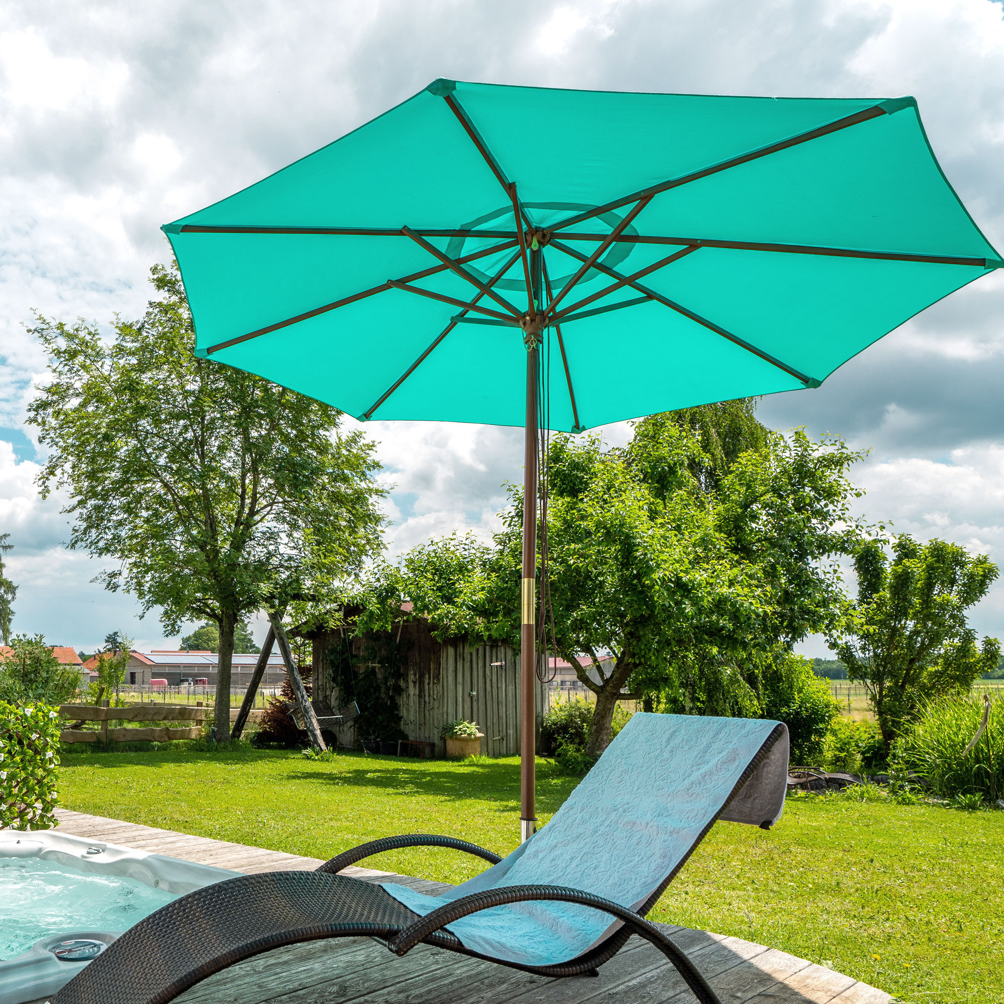 Knickbarer Holz-Sonnenschirm neben Whirlpool und Liegestuhl im Gartenumfeld