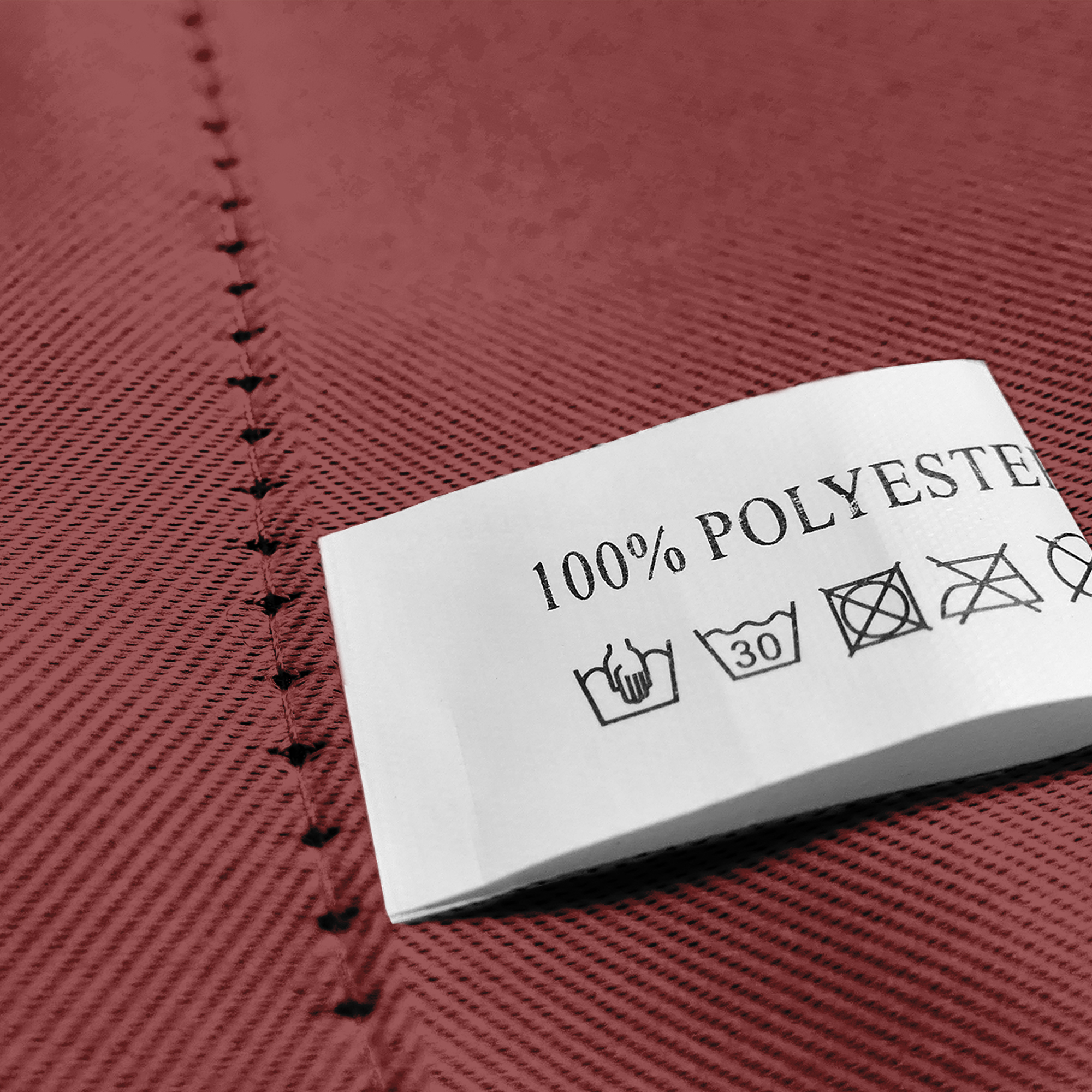 Nahaufnahme eines Stoffes mit Öse und Pflegeetikett aus 100% Polyester