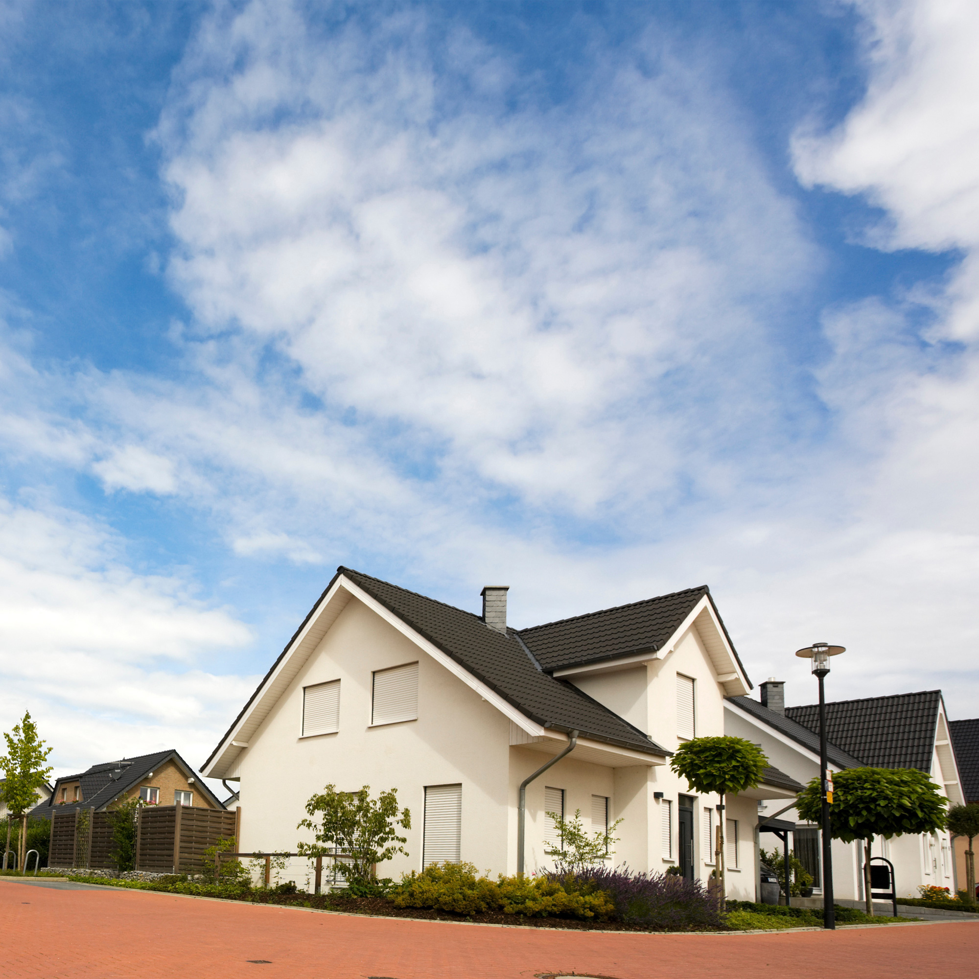 Modernes Einfamilienhaus mit Satteldach und gepflegtem Vorgarten, umgeben von weiteren Häusern