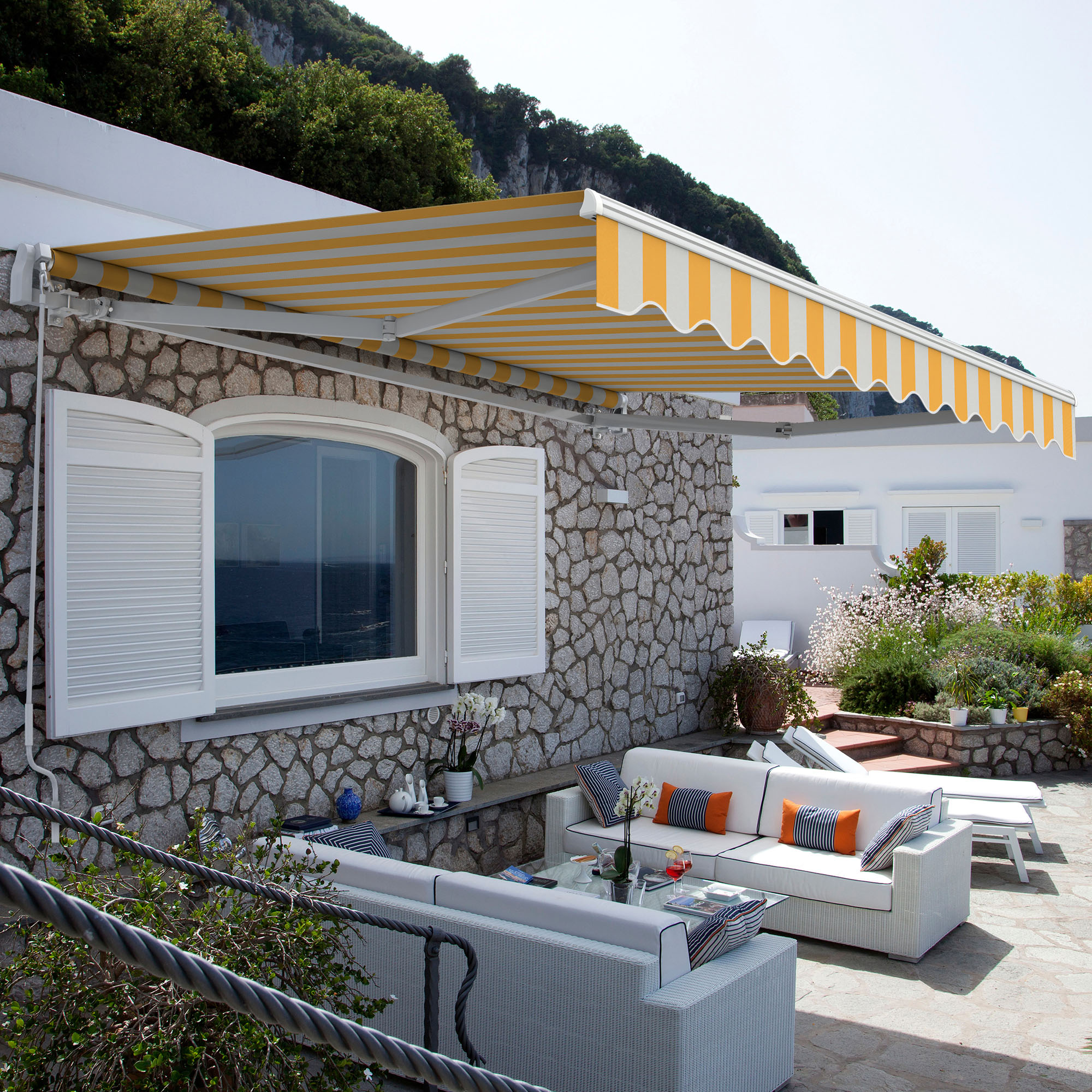 Gelenkarmmarkise über Terrasse an Steinwand montiert, bietet Schatten für Sitzbereich