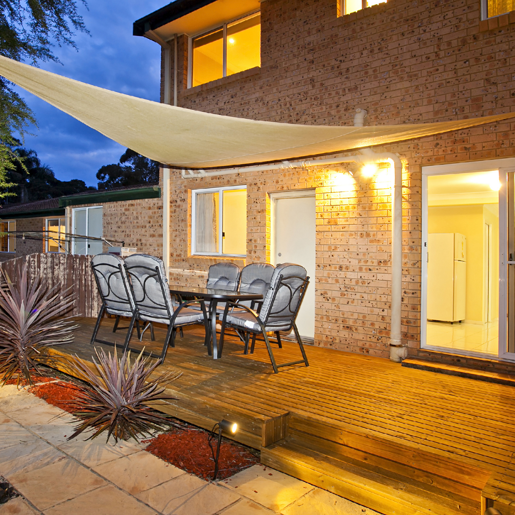Sonnensegel über Terrasse mit Tisch und Stühlen, bietet Schatten und Schutz im Außenbereich