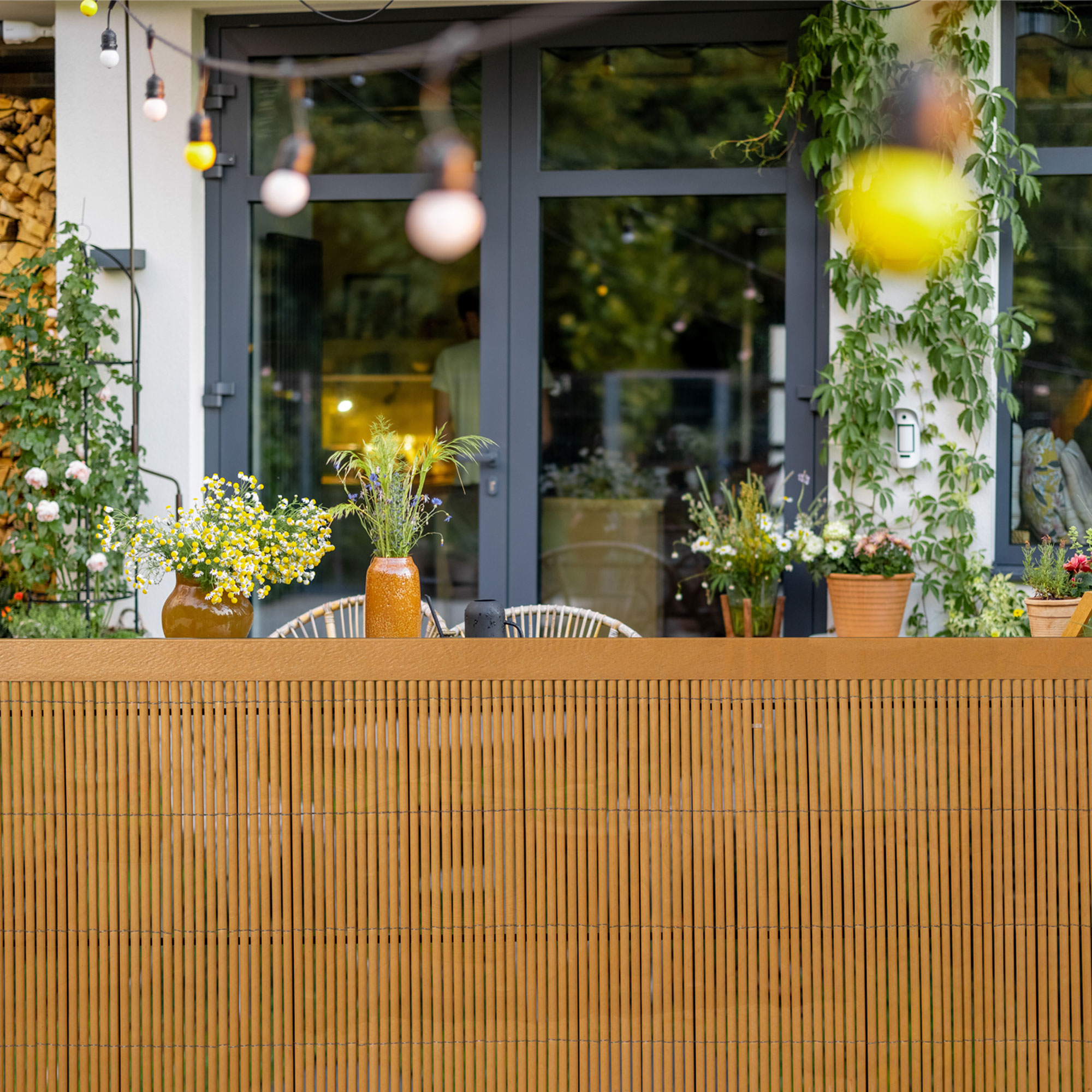 Sichtschutzmatte vor Terrasse mit Pflanzen und Möbeln im Hintergrund