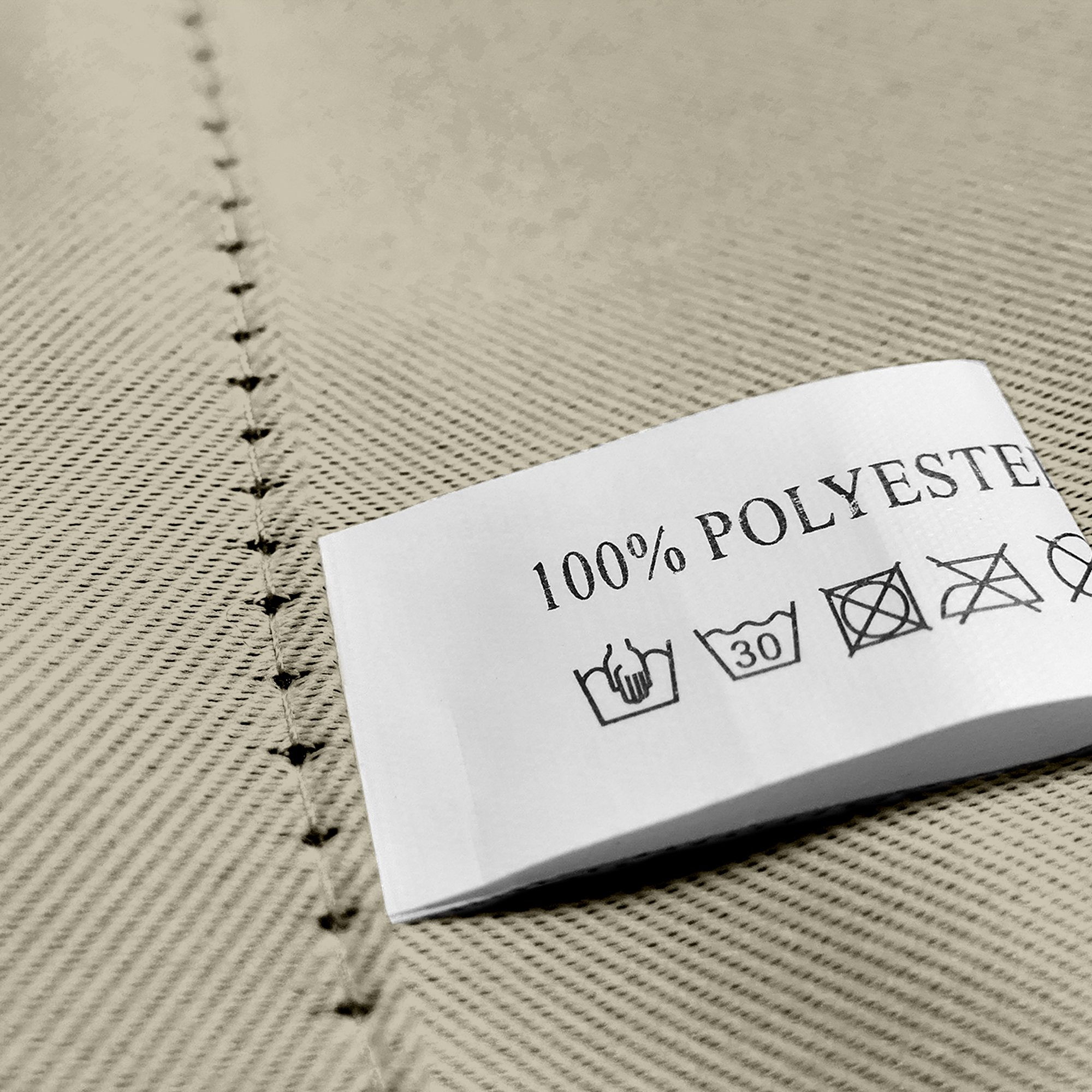 Nahaufnahme eines Stoffes mit Öse und Pflegeetikett aus 100% Polyester