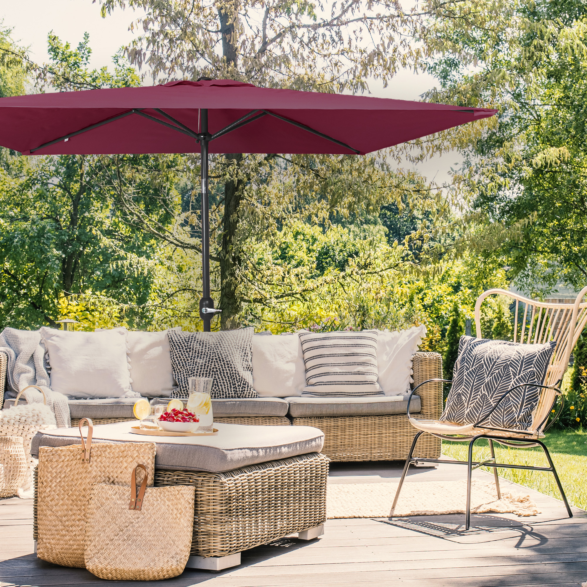 Kleiner, knickbarer Sonnenschirm über einer Terrasse mit Sitzmöbeln und Pflanzen im Hintergrund