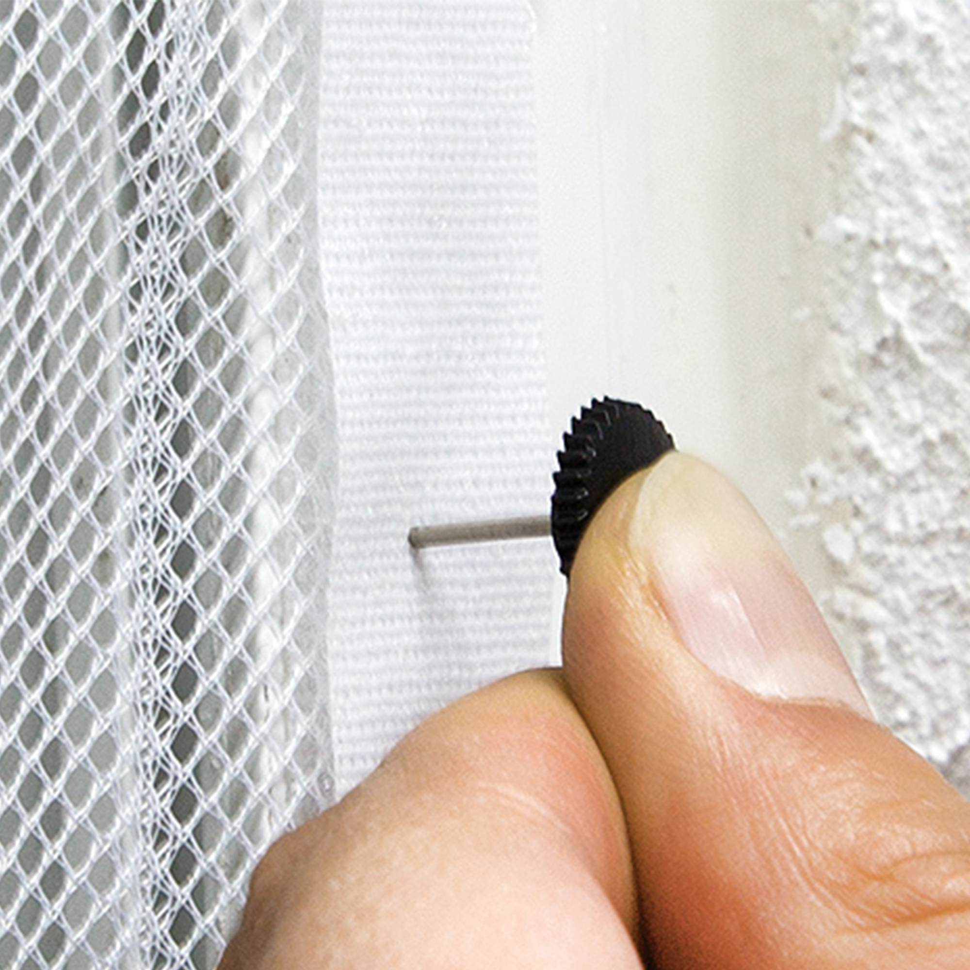 Hand befestigt Netzstoff mit einem kleinen Stift an einer Wandoberfläche