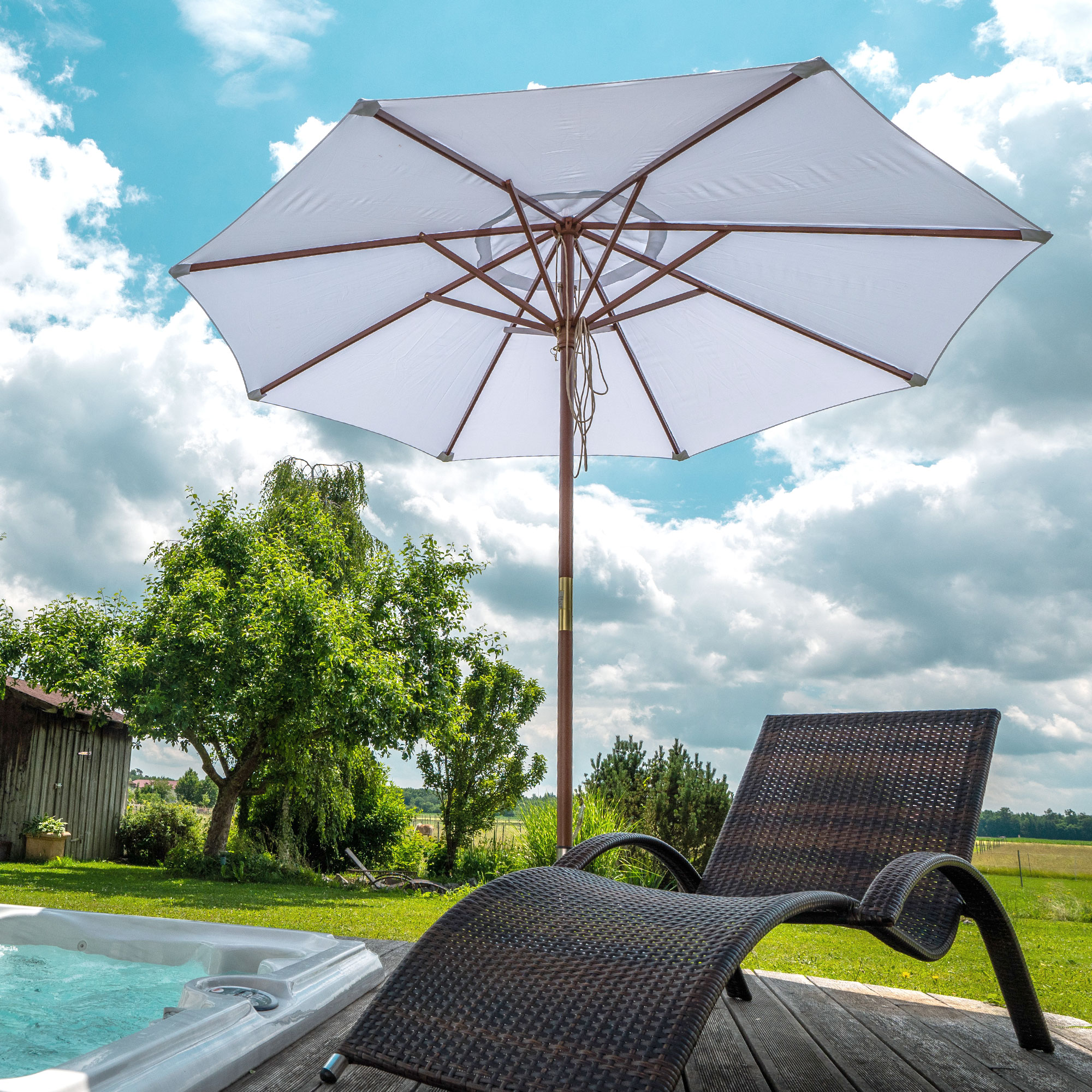Sonnenschirm mit Holzgestell im Garten neben Liegestuhl und Pool