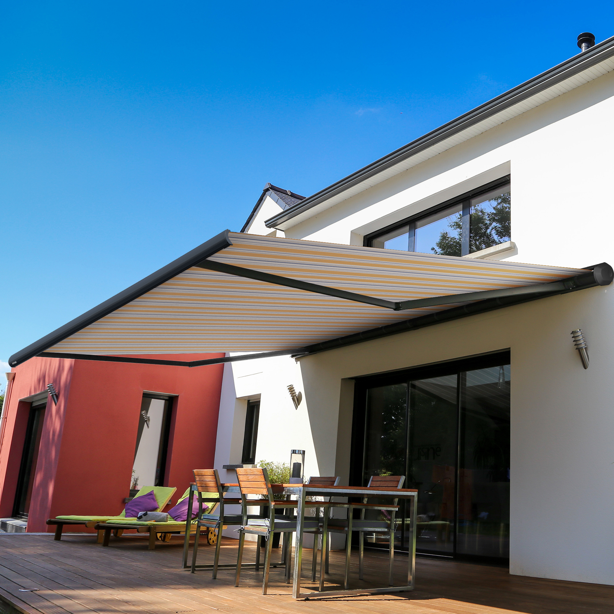 Kassettenmarkise an Hauswand über Terrasse mit Sitzmöbeln und Pflanzen
