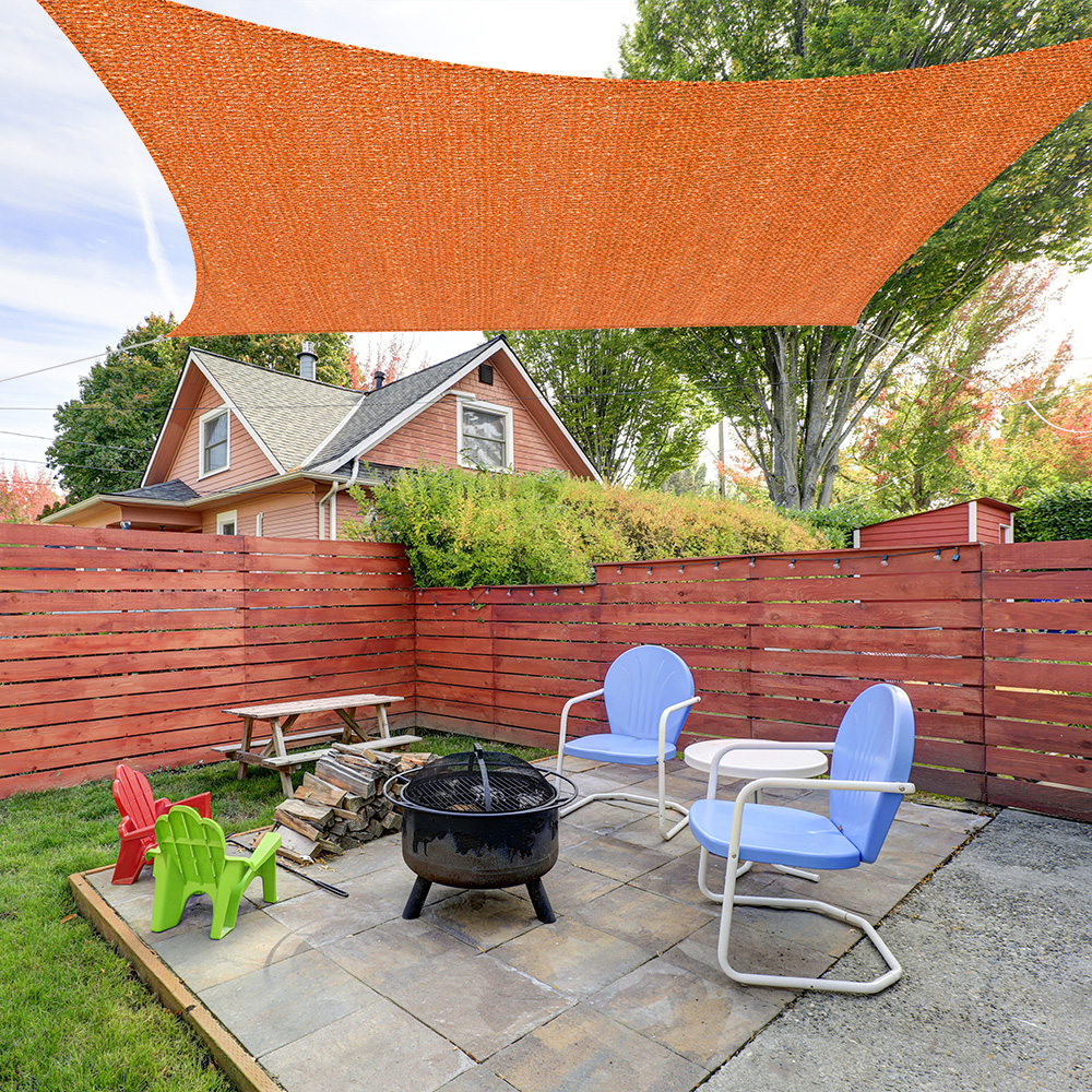 Sonnensegel über Terrasse mit Feuerstelle und Sitzgelegenheiten im Gartenbereich