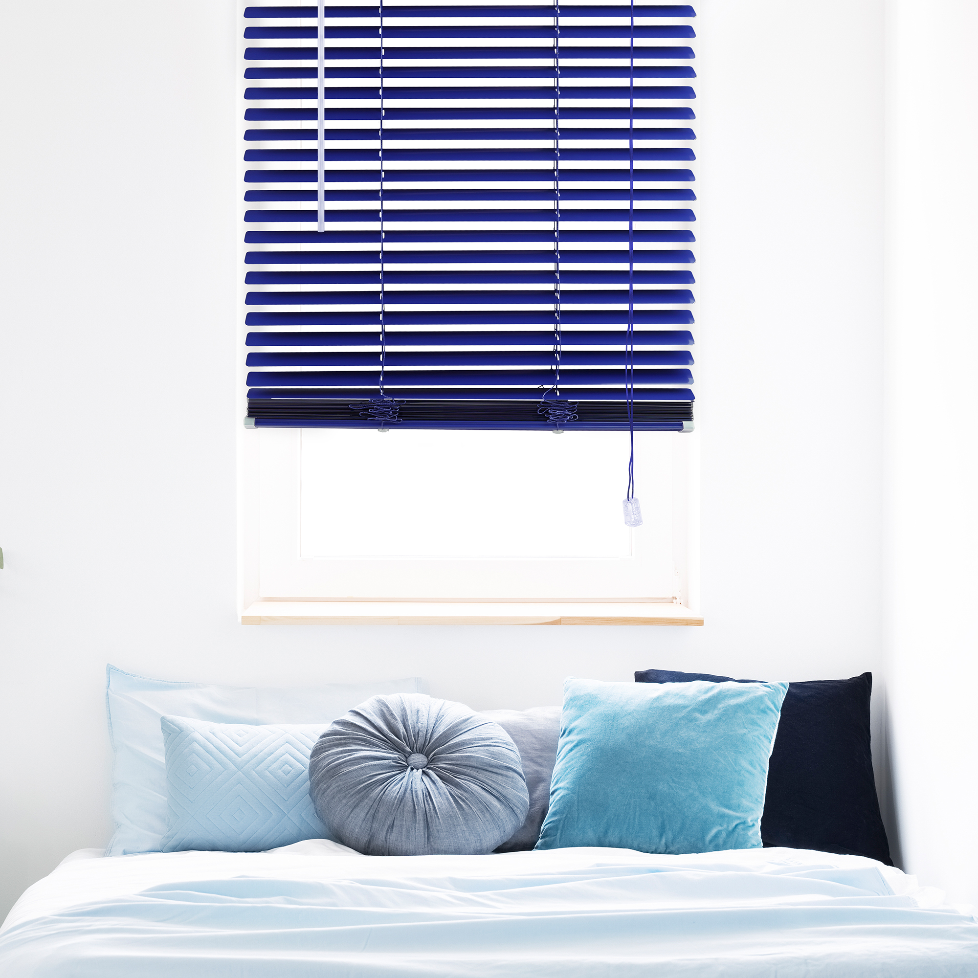 Aluminium Jalousie an einem Fenster über einem Bett in einem modern eingerichteten Raum