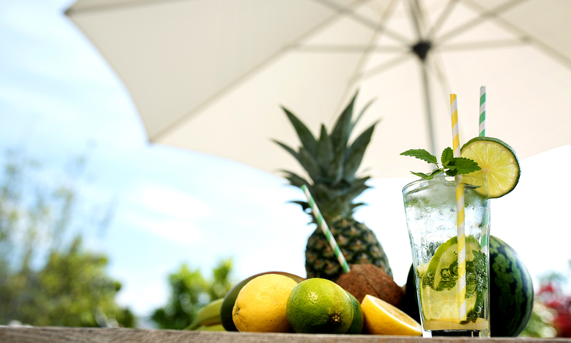 Getränk und Früchte auf Tisch unter Sonnenschirm