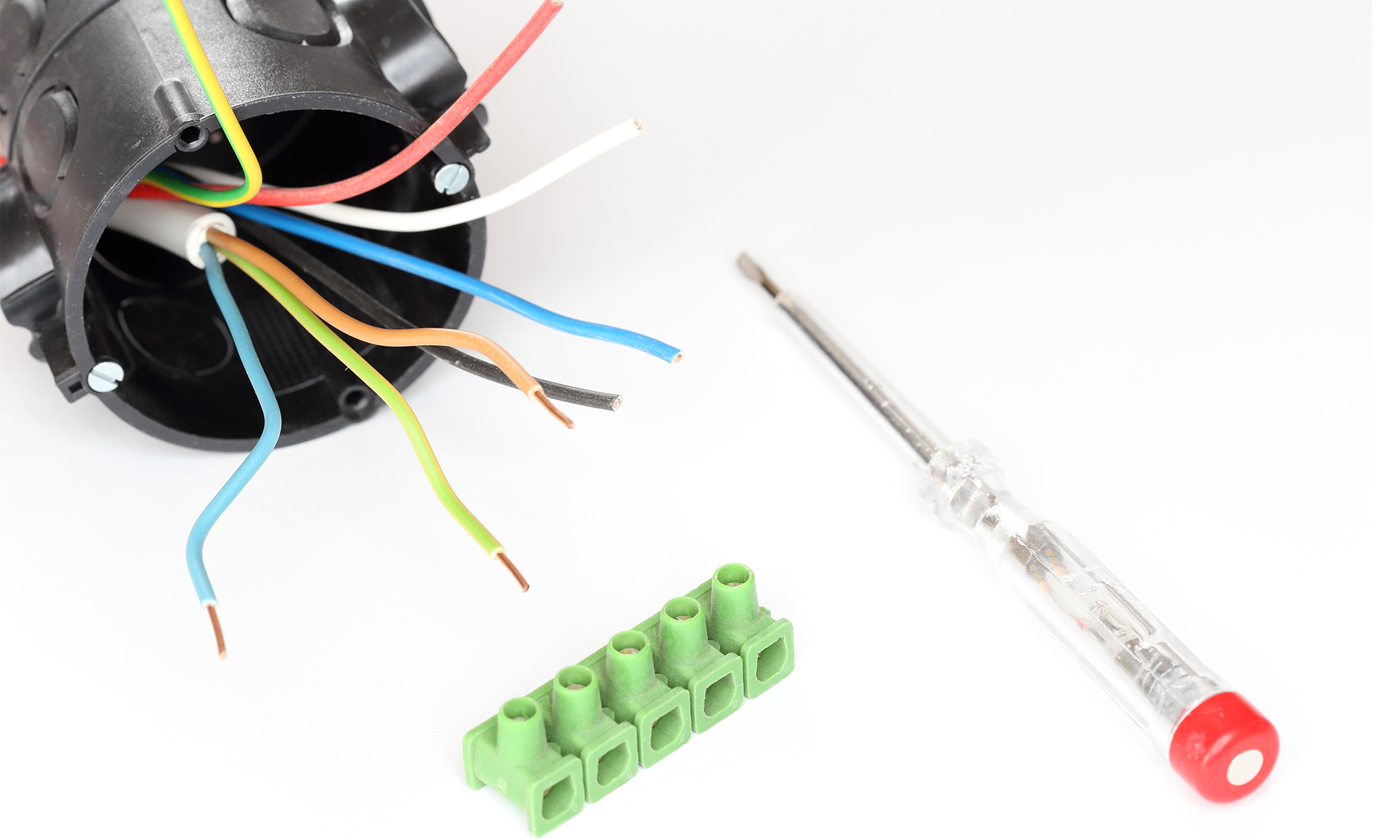 Unterputzdose mit herausragenden Kabeln, daneben ein Schraubendreher und ein Steckverbinder