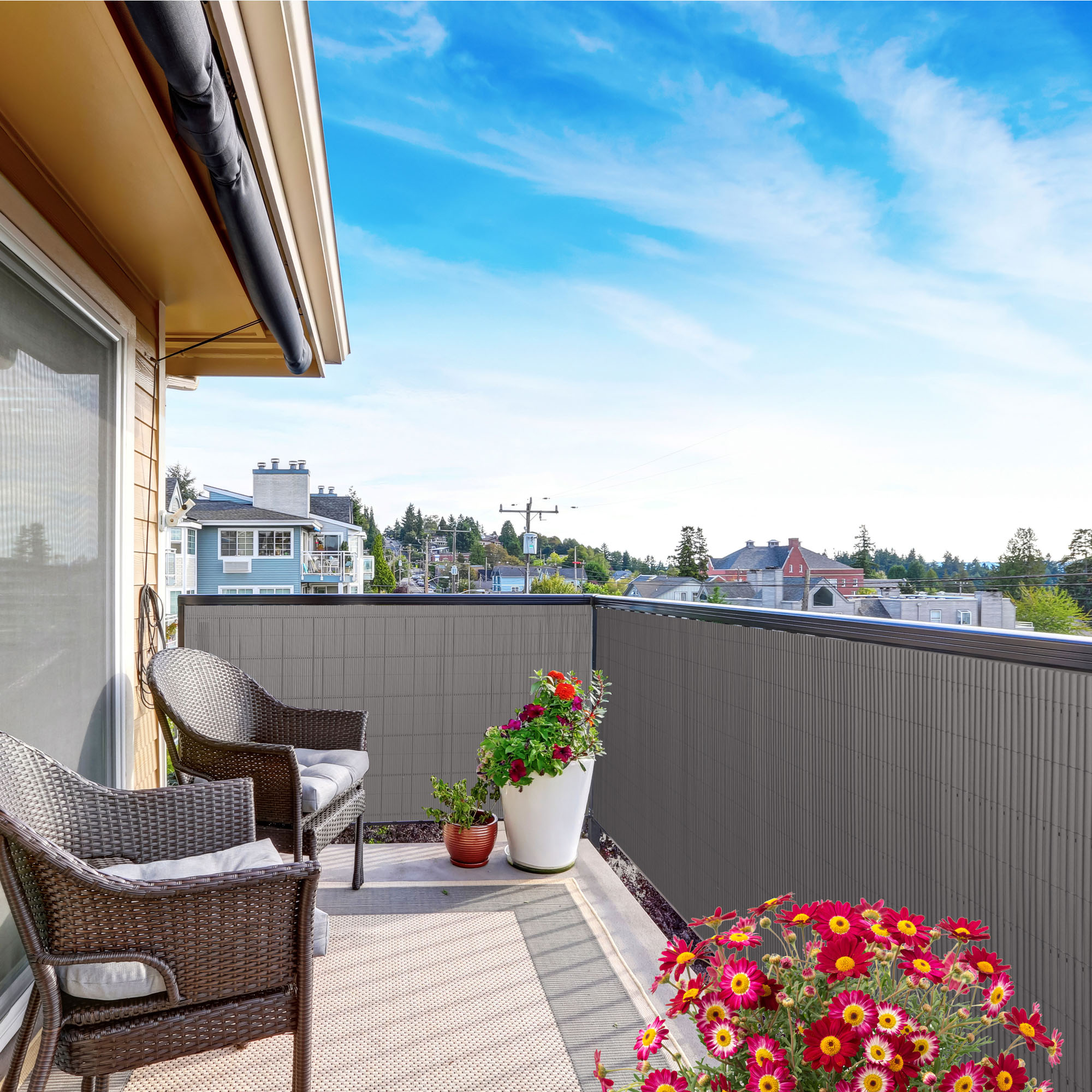 slider_image_e2d348c07a6d4df9b9373d58e507c8a7 Balkon mit Sichtschutzmatte und Abdeckprofil, zwei Stühle, Pflanzen, Ausblick auf Häuser und Bäume