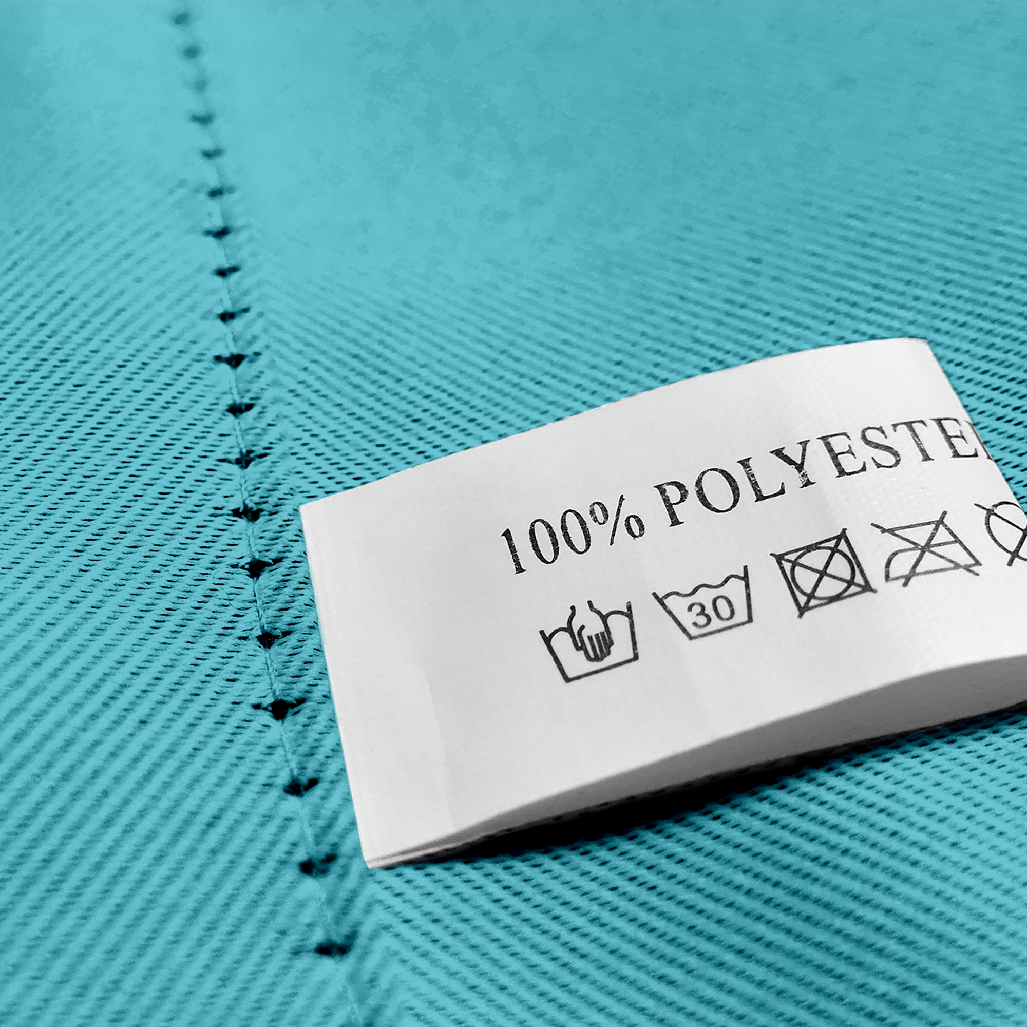 Nahaufnahme eines Stoffes mit Öse und Pflegeetikett aus 100% Polyester