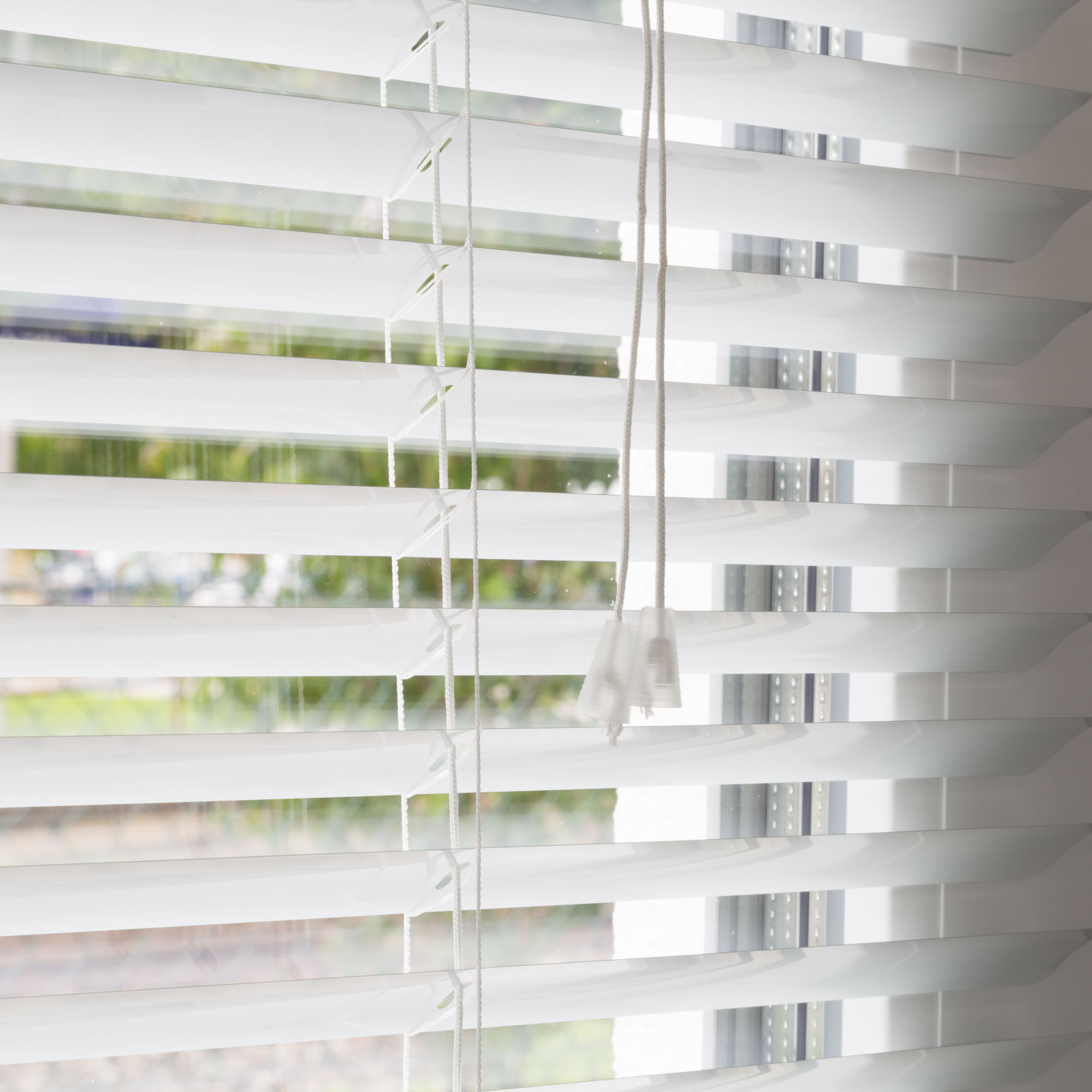 Aluminium Jalousie mit Lamellen und Zugkordel vor einem Fenster