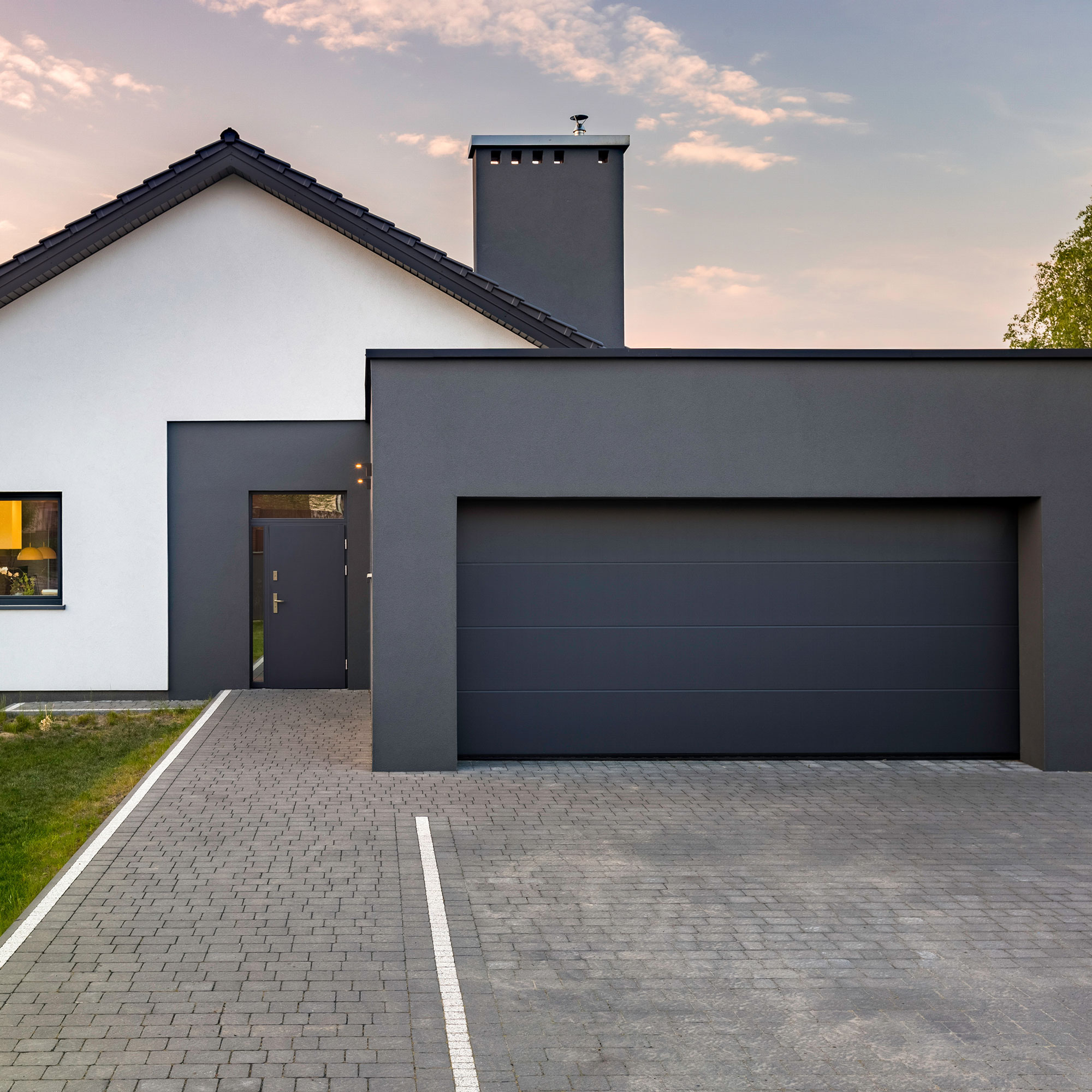 Modernes Haus mit Garagentor und gepflasterter Einfahrt