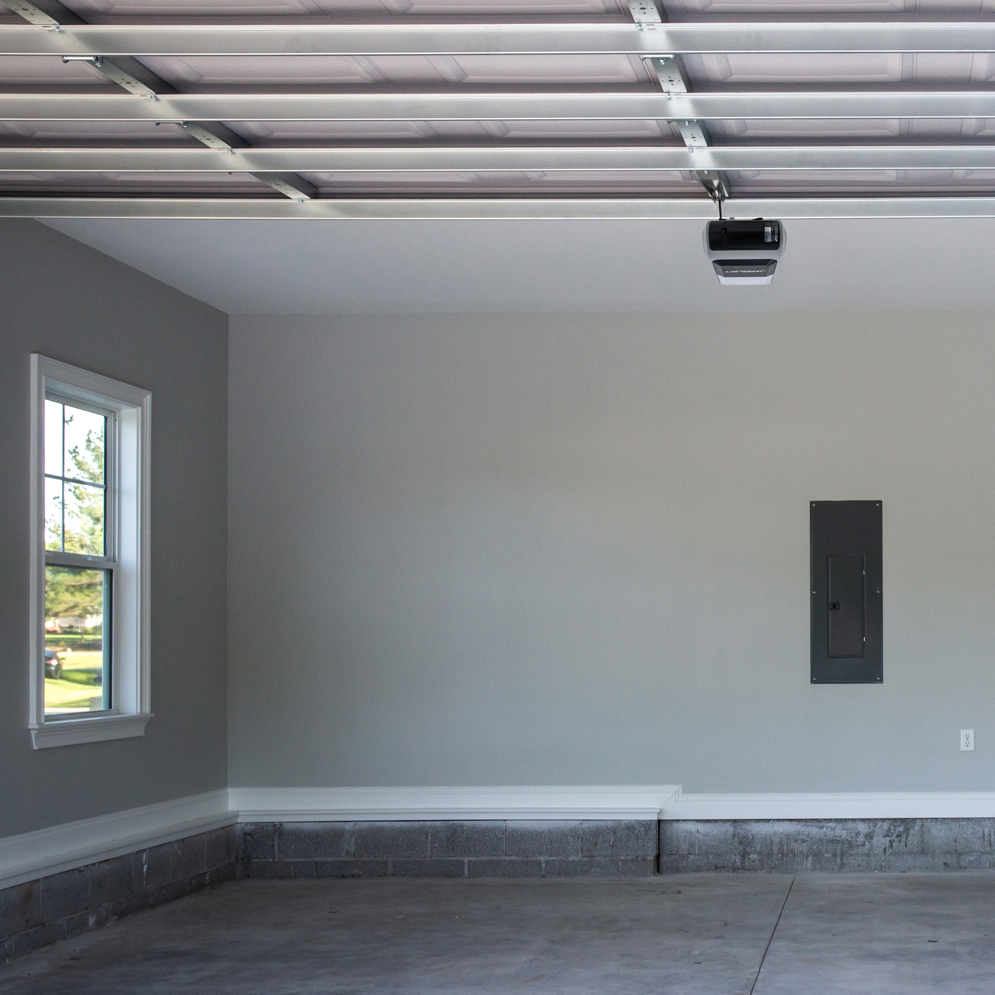 Leere Garage mit geschlossenem Garagentor und Fenster an der linken Wand