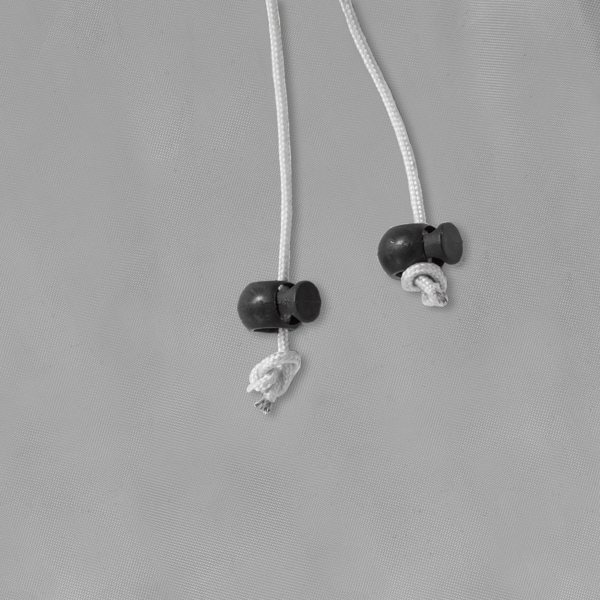 Zwei Kordeln mit Stoppern auf einer textilen Oberfläche