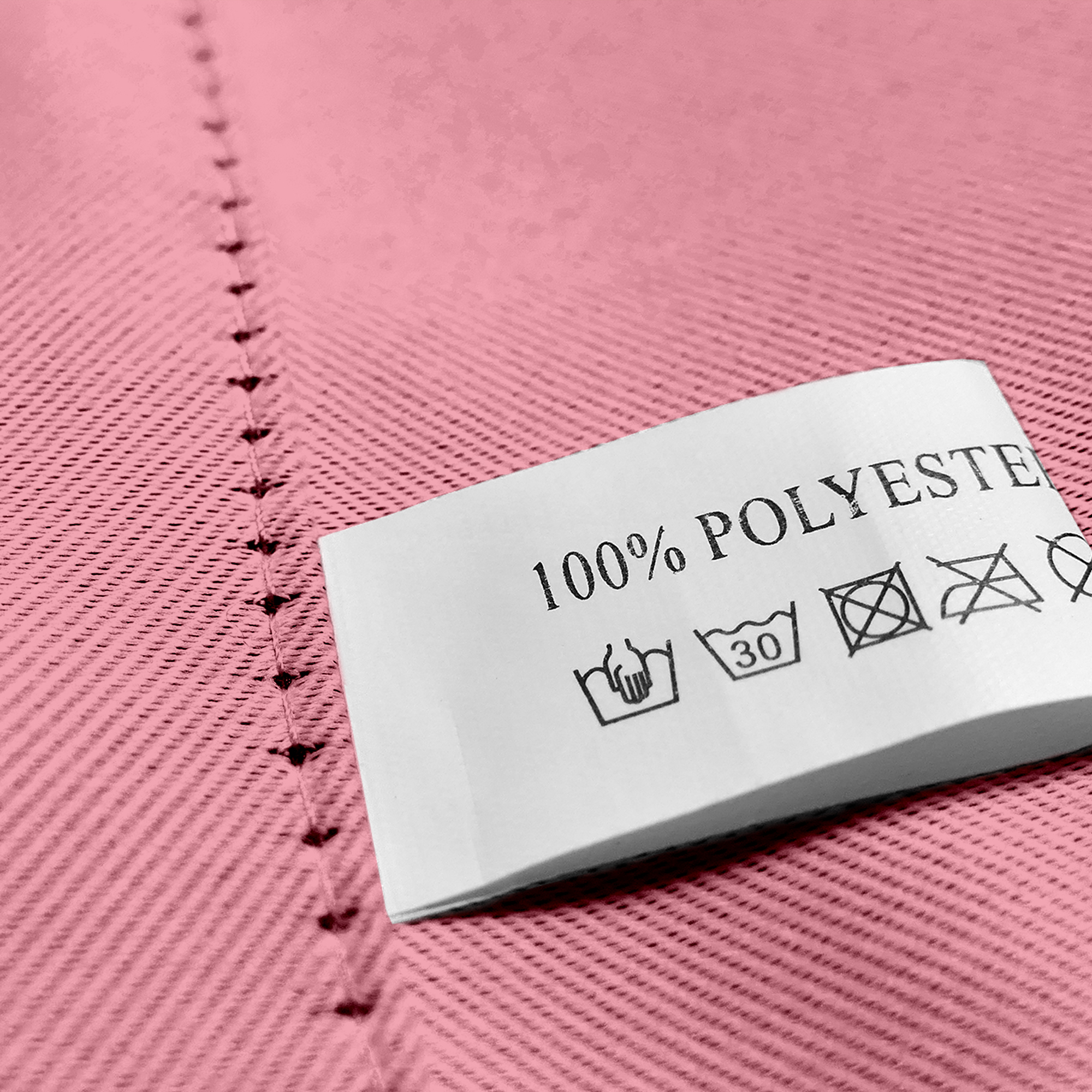 Nahaufnahme eines Stoffes mit Öse und Pflegeetikett aus 100% Polyester