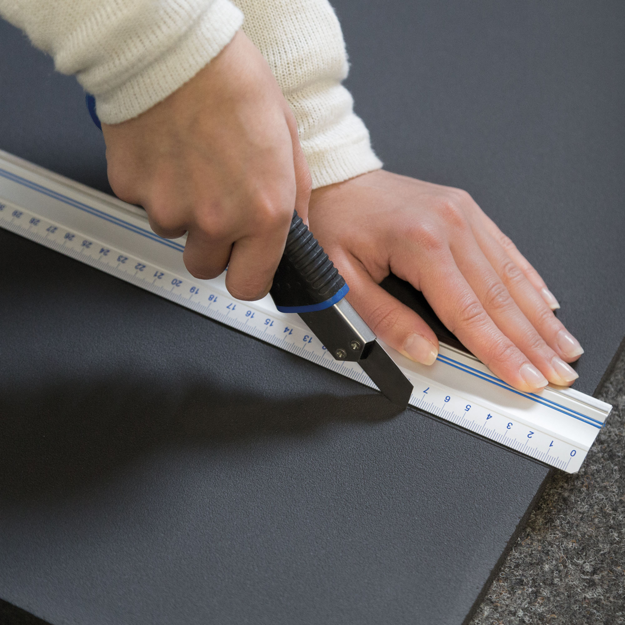 Person schneidet Isoliermatte mit Cutter und Lineal