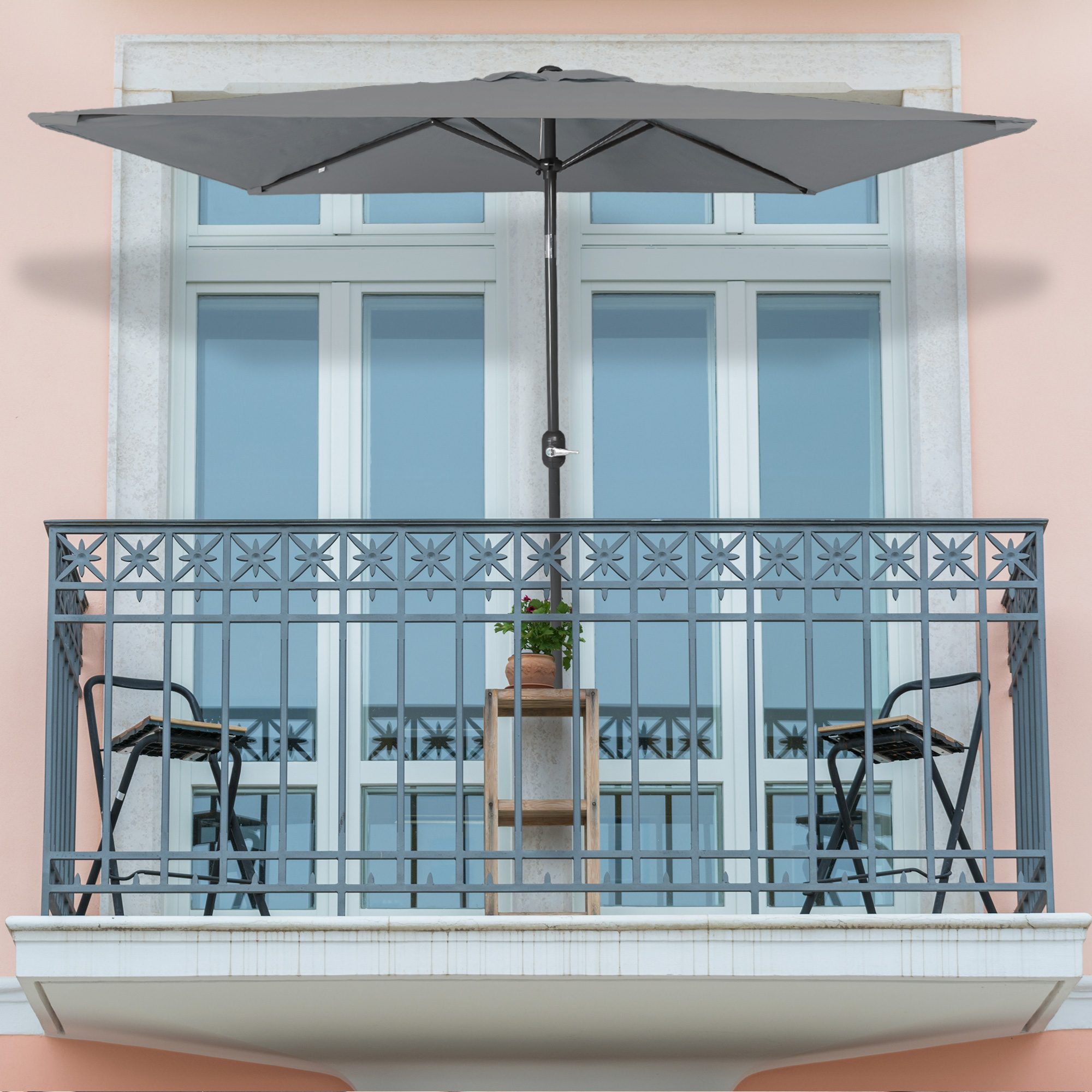 Kleiner, knickbarer Sonnenschirm auf einem Balkon über Tisch und Stühlen