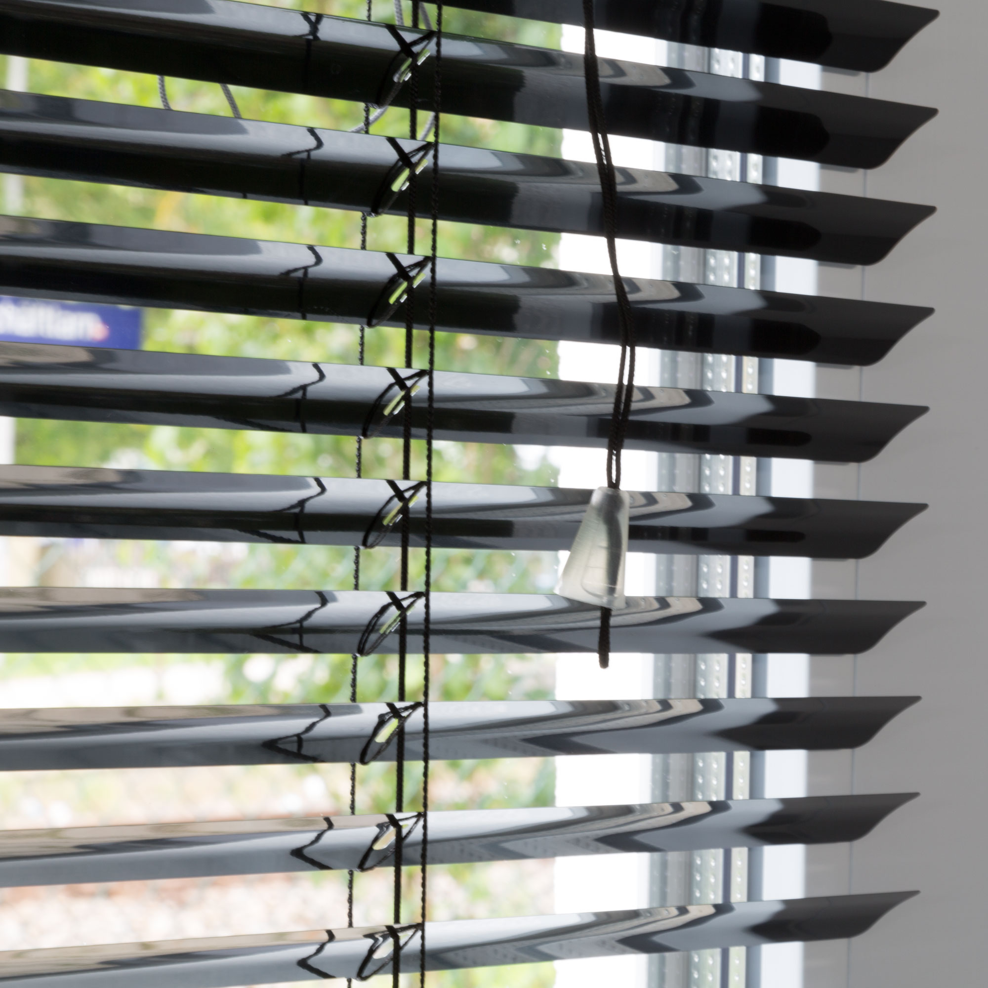 Aluminium Jalousie mit Lamellen und Zugkordel vor einem Fenster