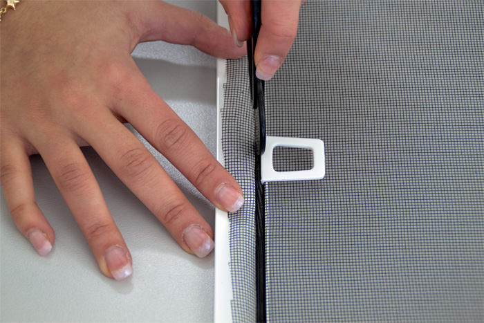 Hände verwenden PVC-Werkzeug zum Befestigen von Insektenschutz in Spannrahmen