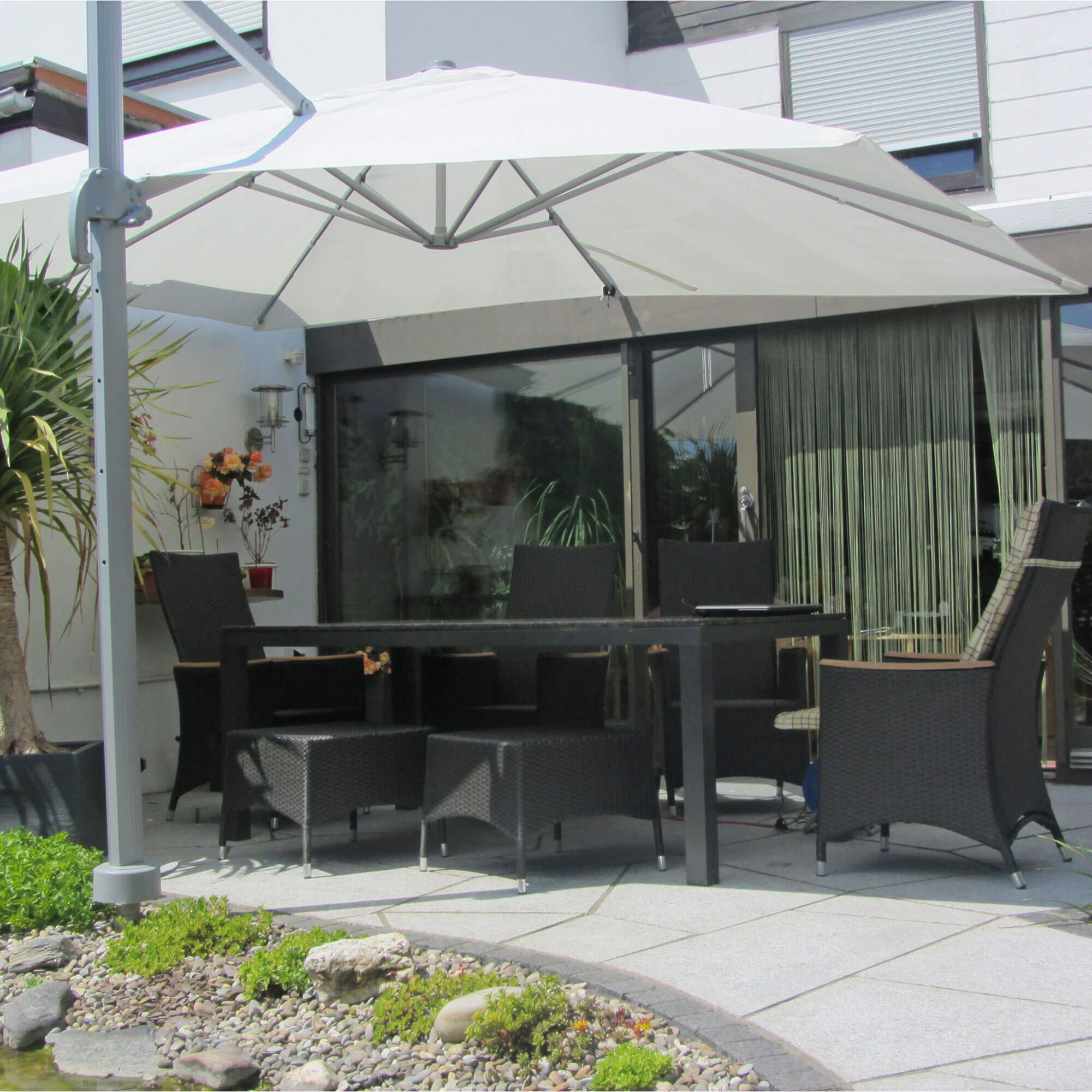 slider_image_470615754e2a444aa4ba17454abe7c4a Terrasse mit Ampelschirm und Gartenmöbeln, umgeben von Pflanzen und einem kleinen Teich