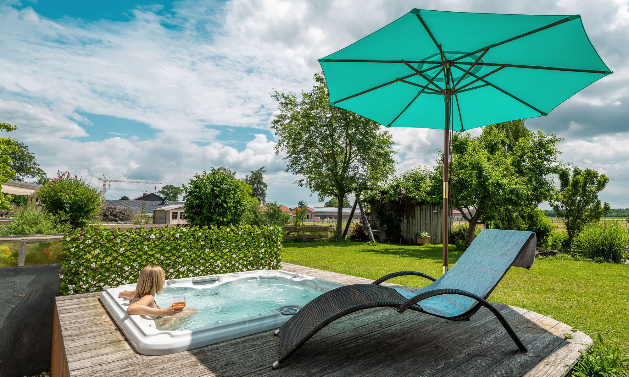 slider_image_5192e41f6457478bb12a7084841dce56 Knickbarer Holz-Sonnenschirm neben Whirlpool und Liegestuhl im Gartenumfeld