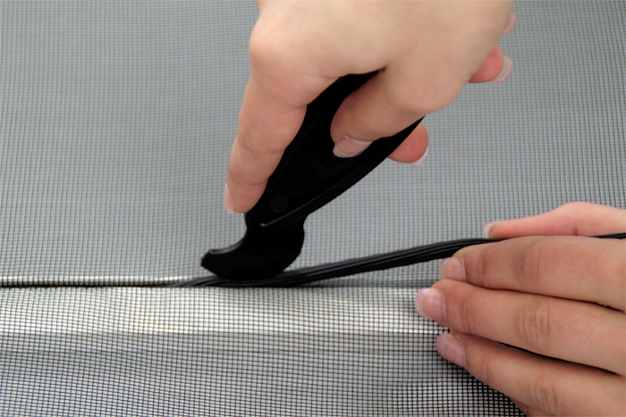 Werkzeug zum Einsetzen von Keder in Insektenschutz-Spannrahmen, Hand hält und führt es